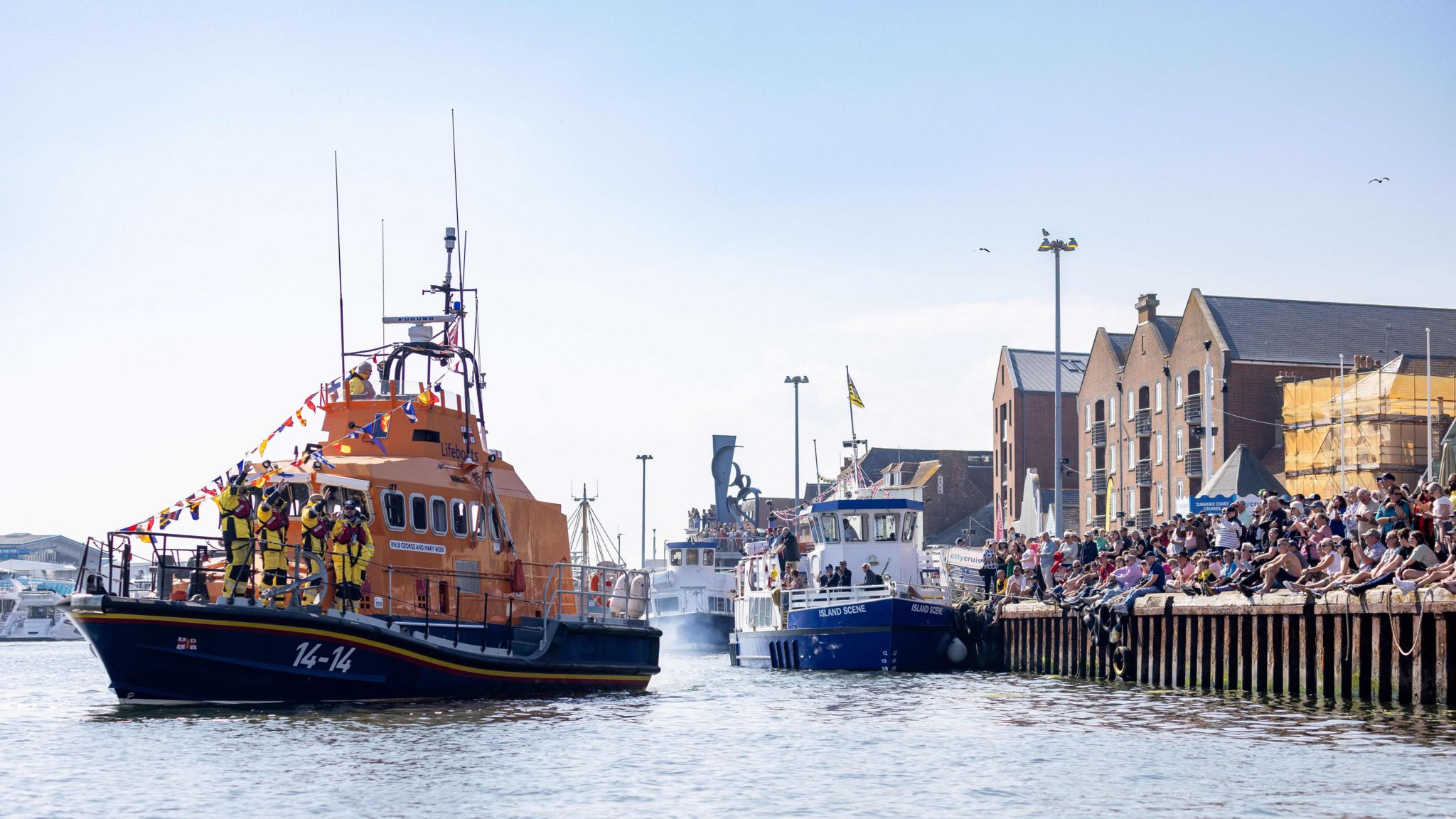 A Trent class all-weather lifeboat taking part in the flotilla as crowds gather Poole Quay.