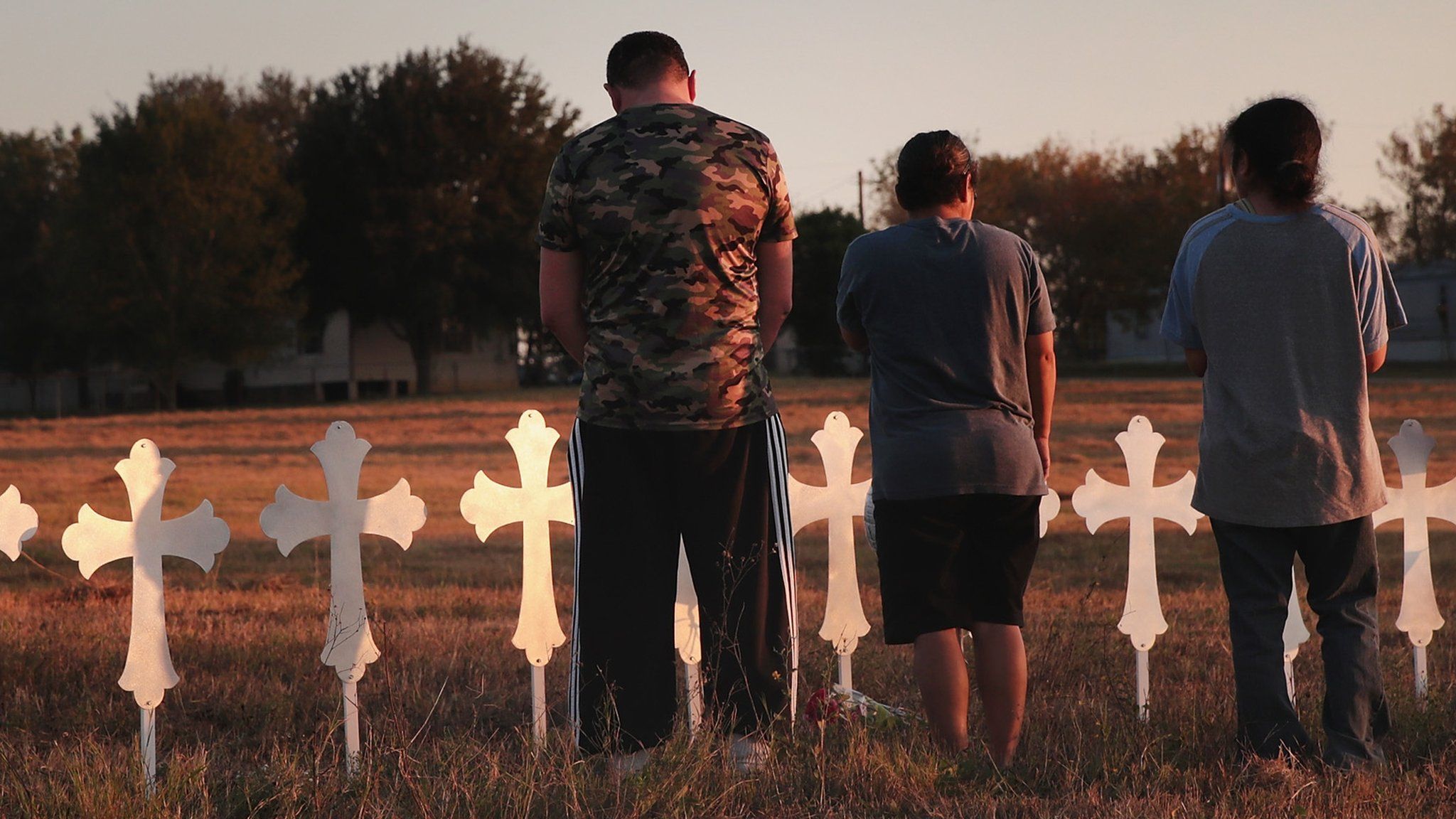 three people stand by memorial crosses after texas shooting