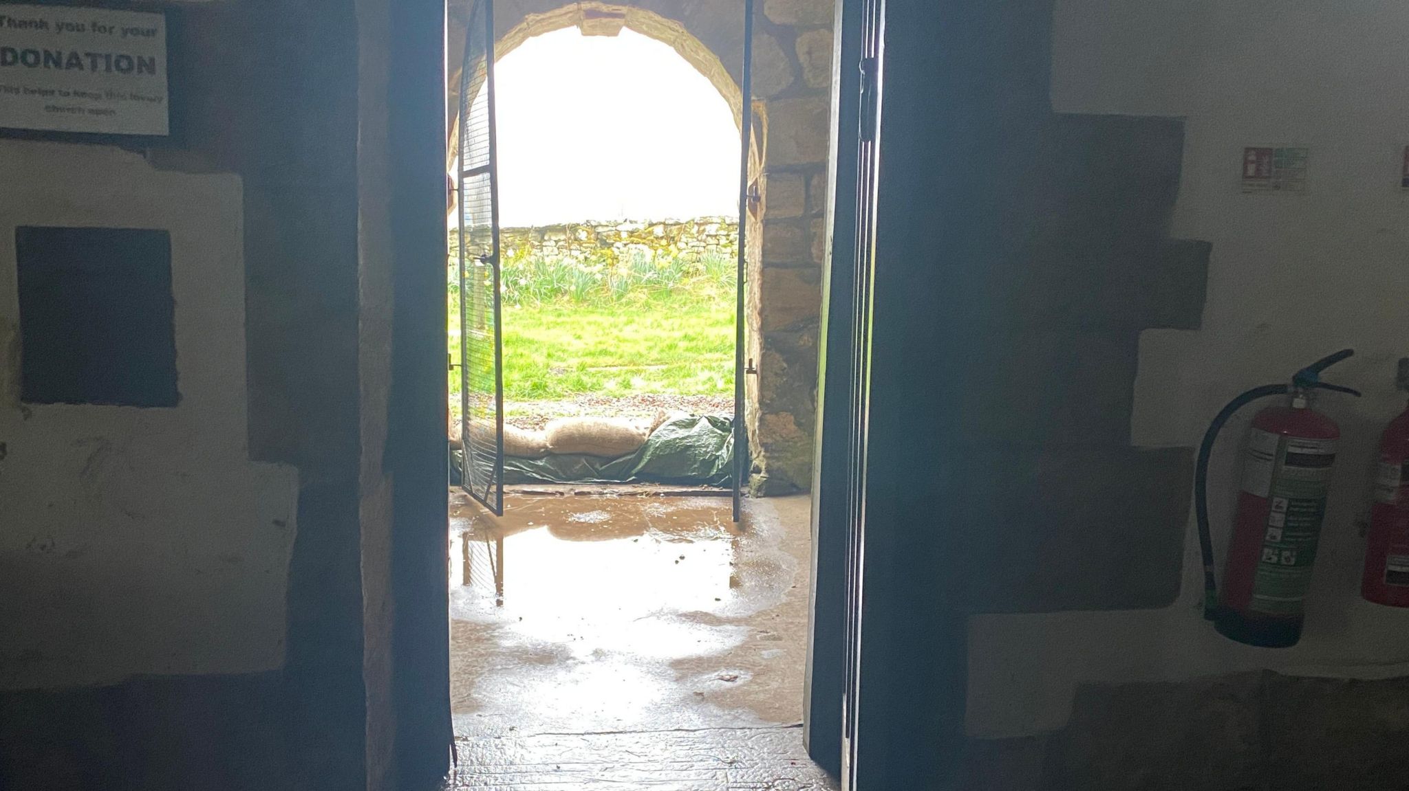 A church door from the inside of the church showing sandbags at the door