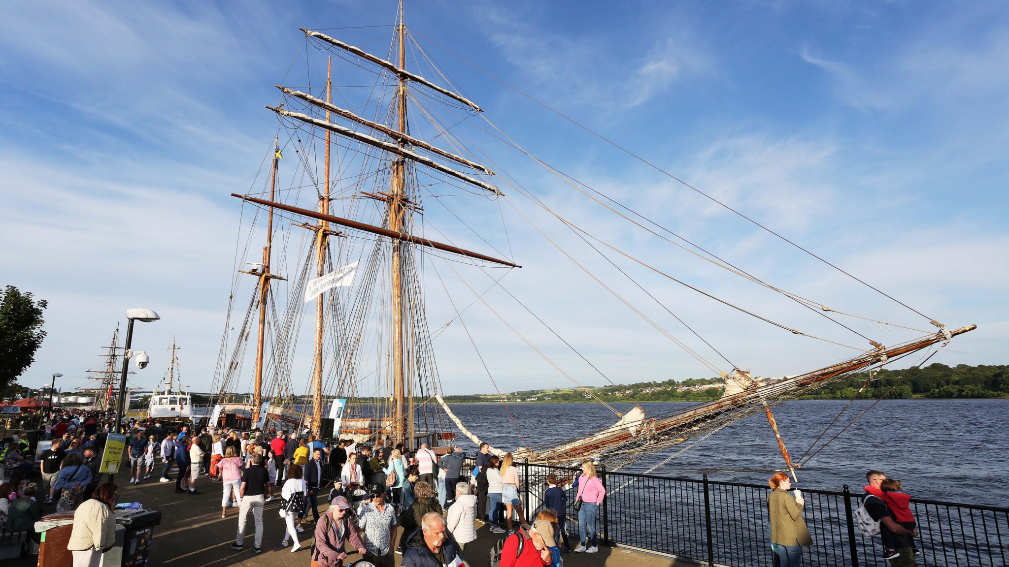 One of the tall ships berthed in Derry for the martime festival, with people walking past in the foreground