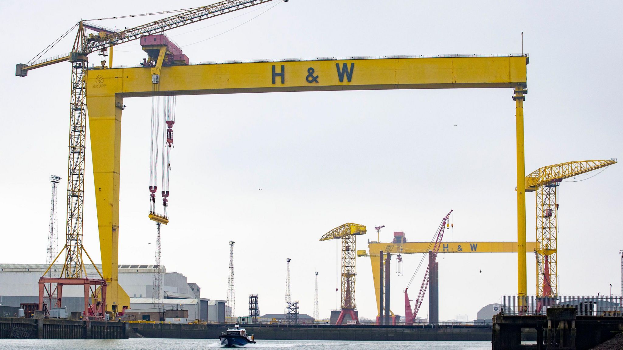 The yellow cranes of Harland and Wolff shipyard set against a grey sky