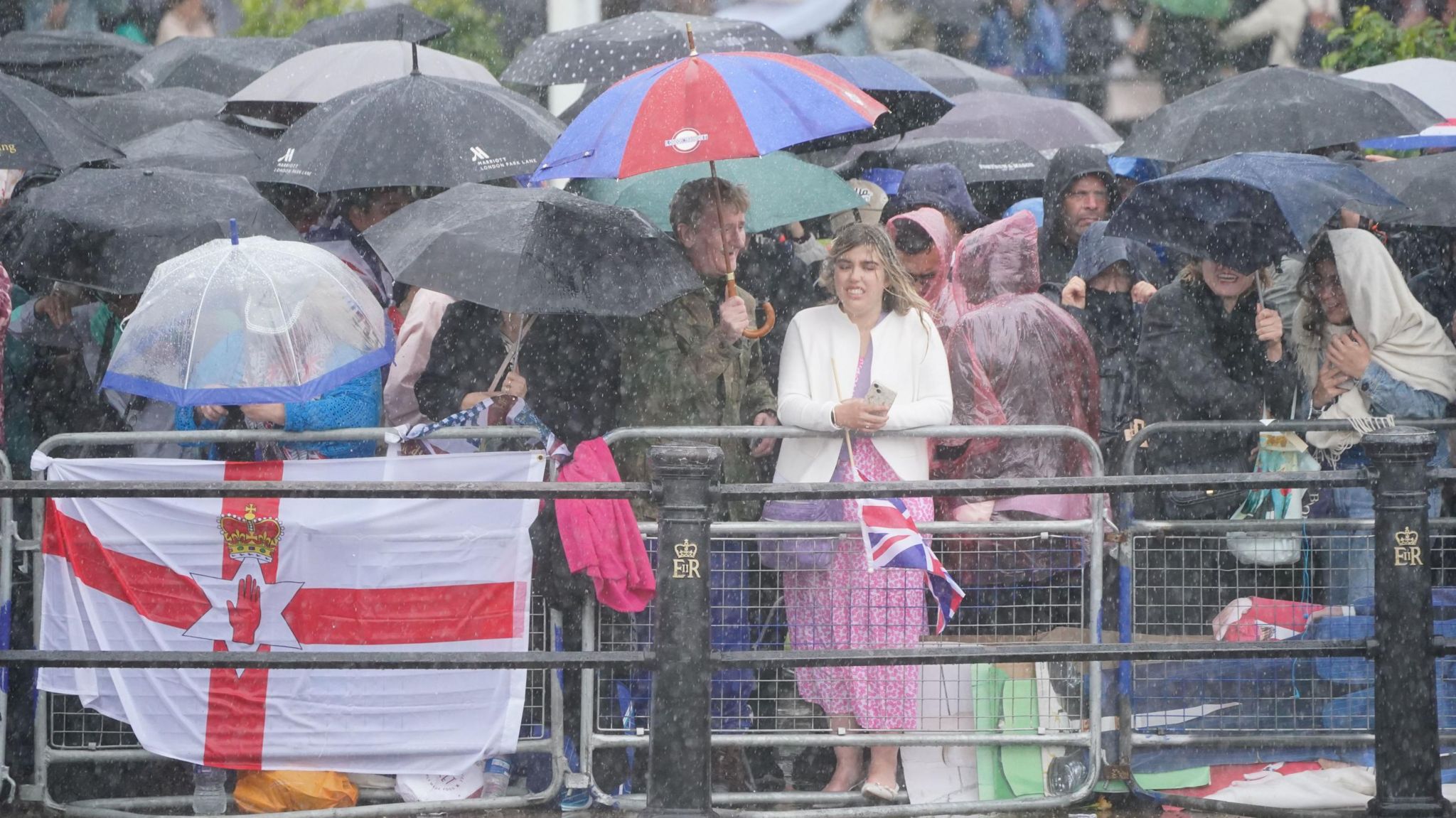 People huddled together under umbrellas behind short fences