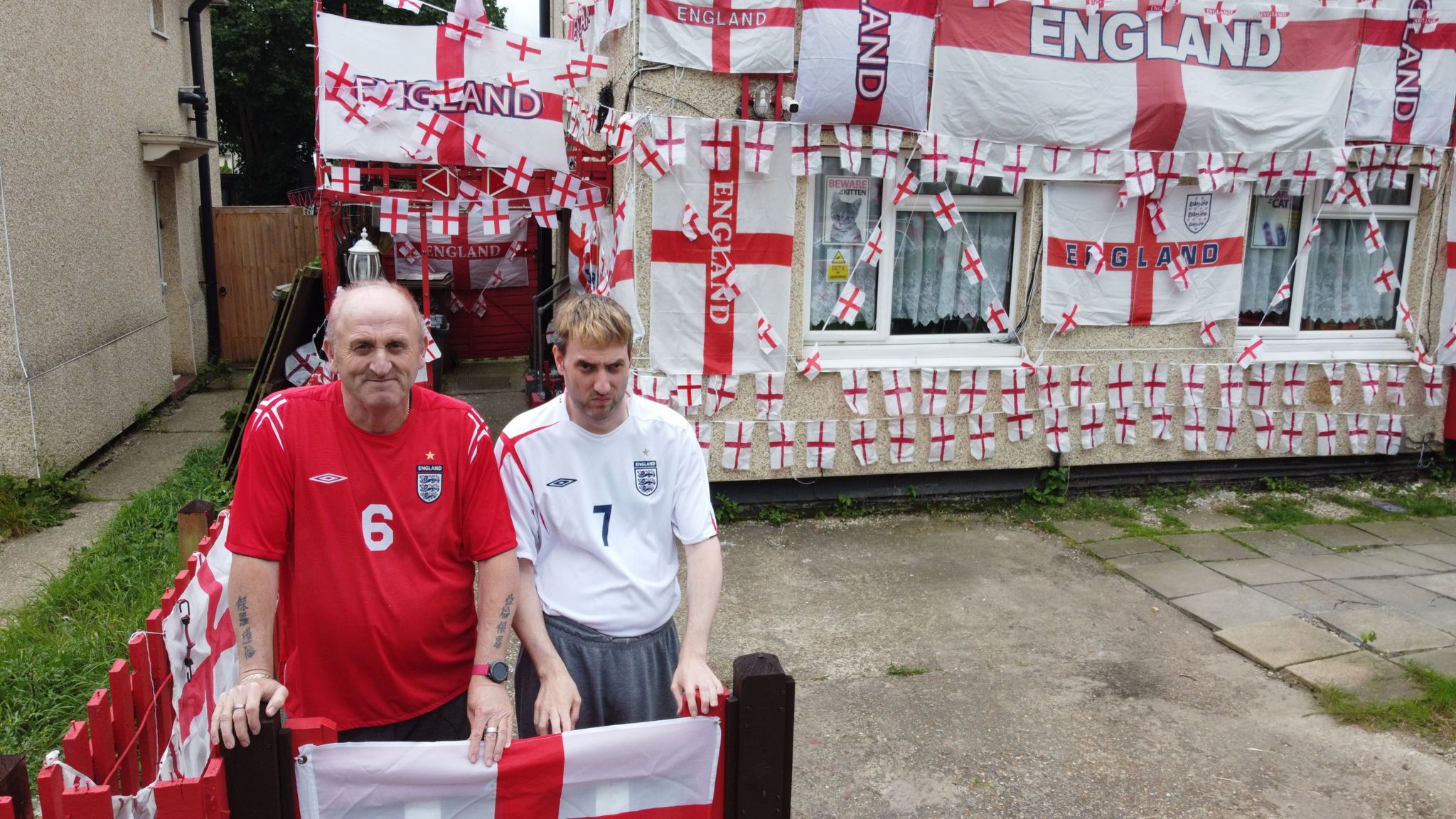 Paul Bibby and his son Aaron sitting in front of their home which is covered in England flags