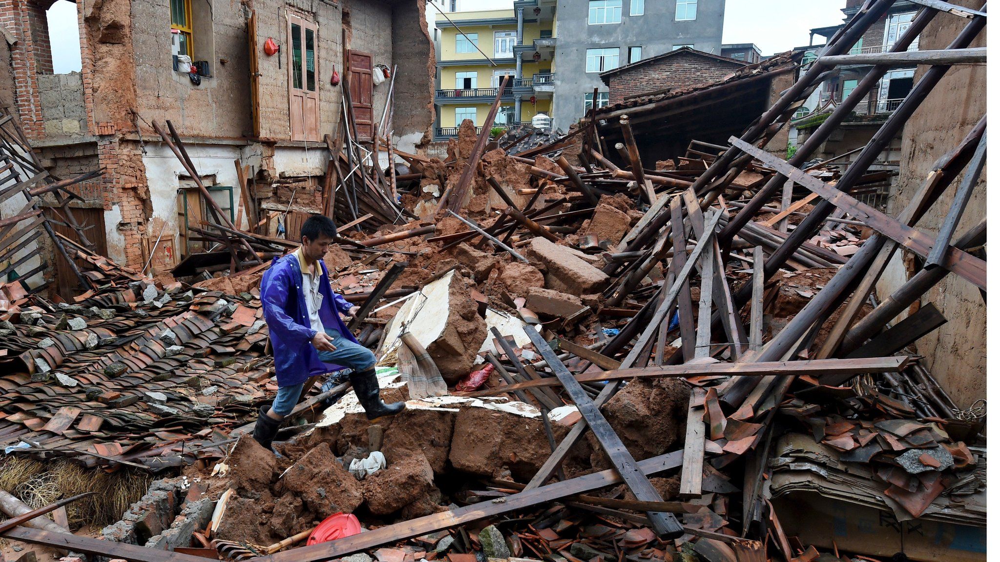 A man walks over debris from destroyed buildings in Putian city in Fujian province on 9 July 2016.