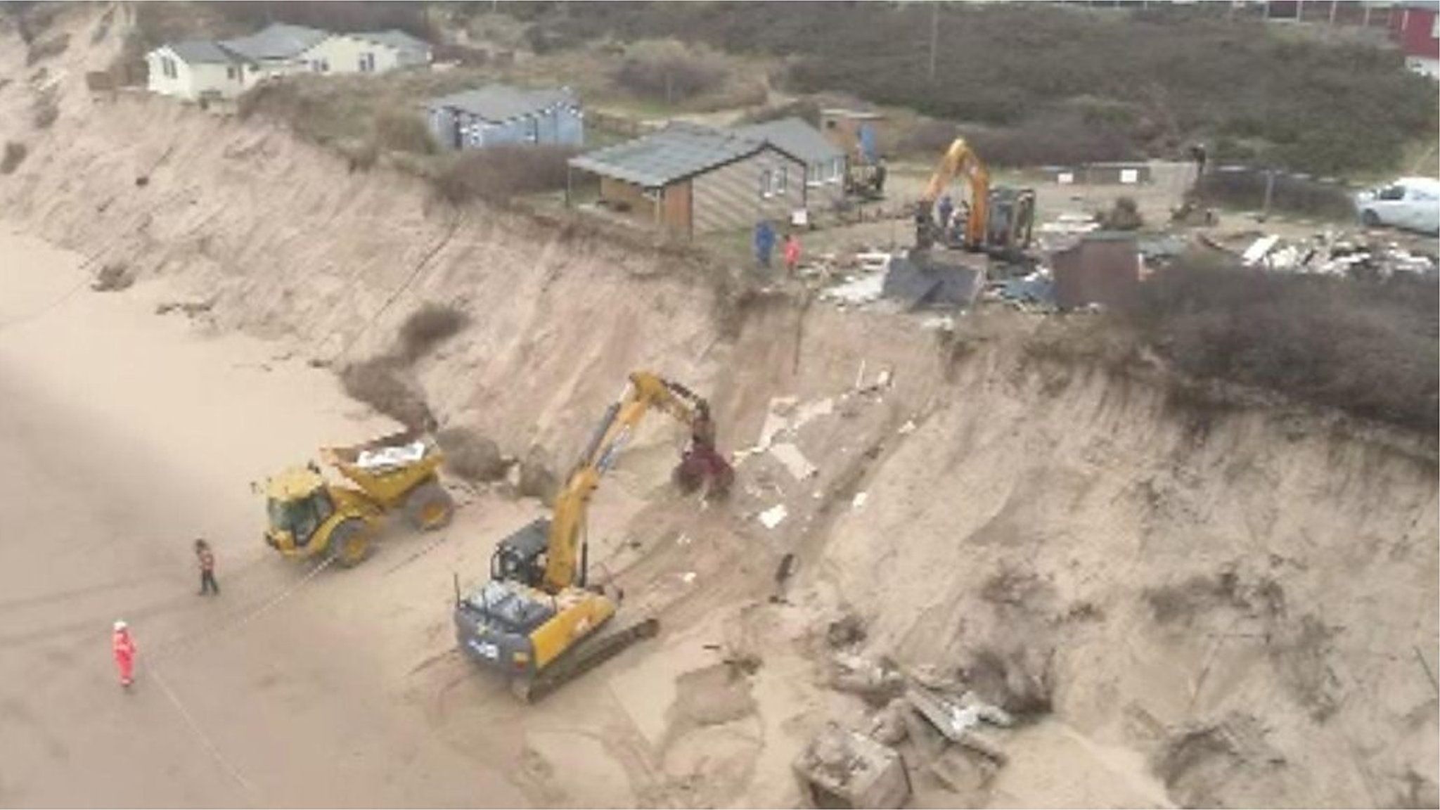 Heavy machinery pulling down cliff-top house