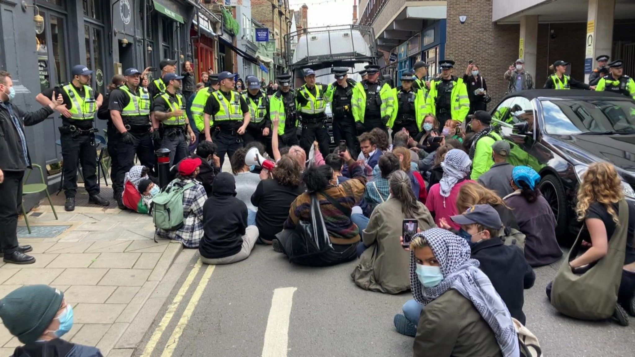 People sitting on the street in front of police