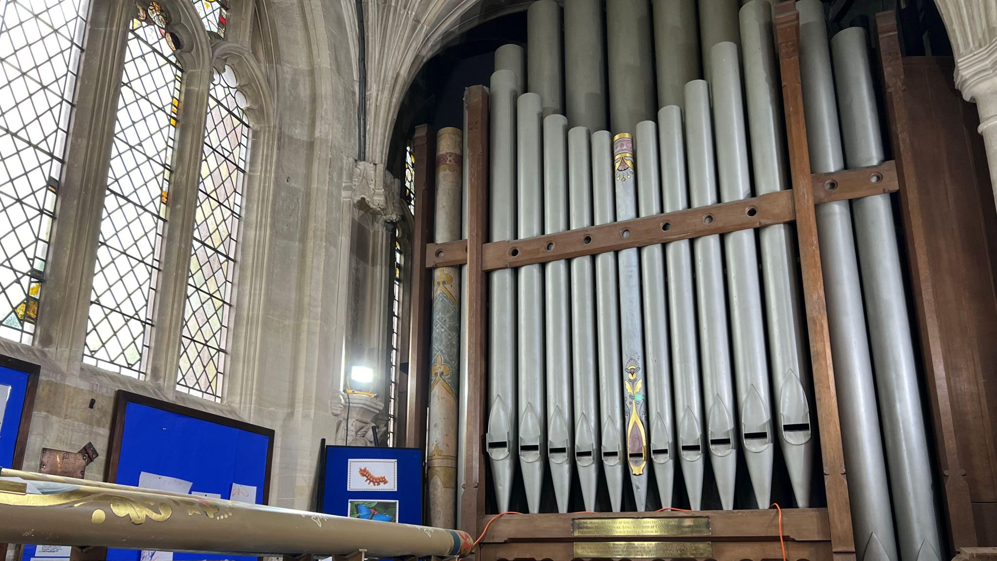 Church organ with mostly grey pipes, but one or two with decoration uncovered