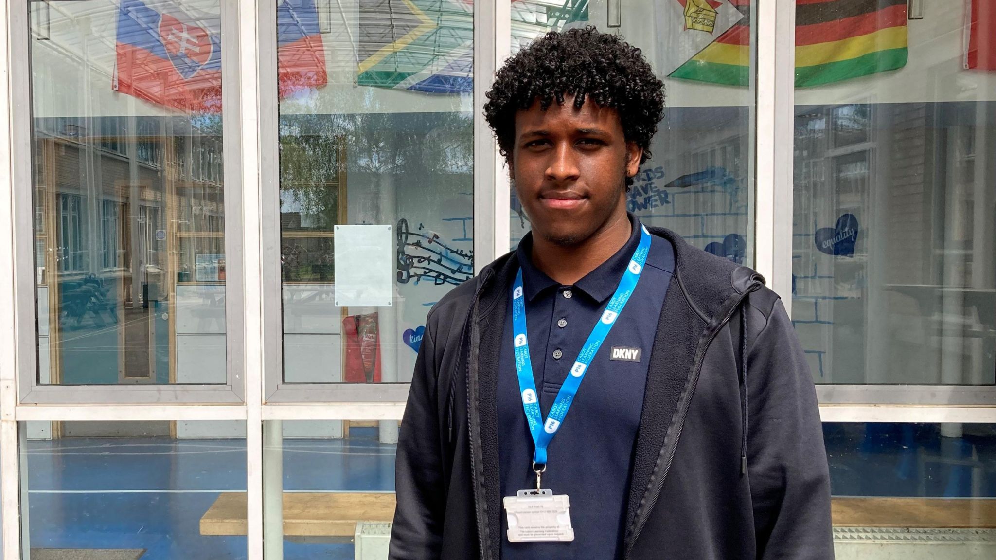 Abdirisaq stood infront of a glass fronted building