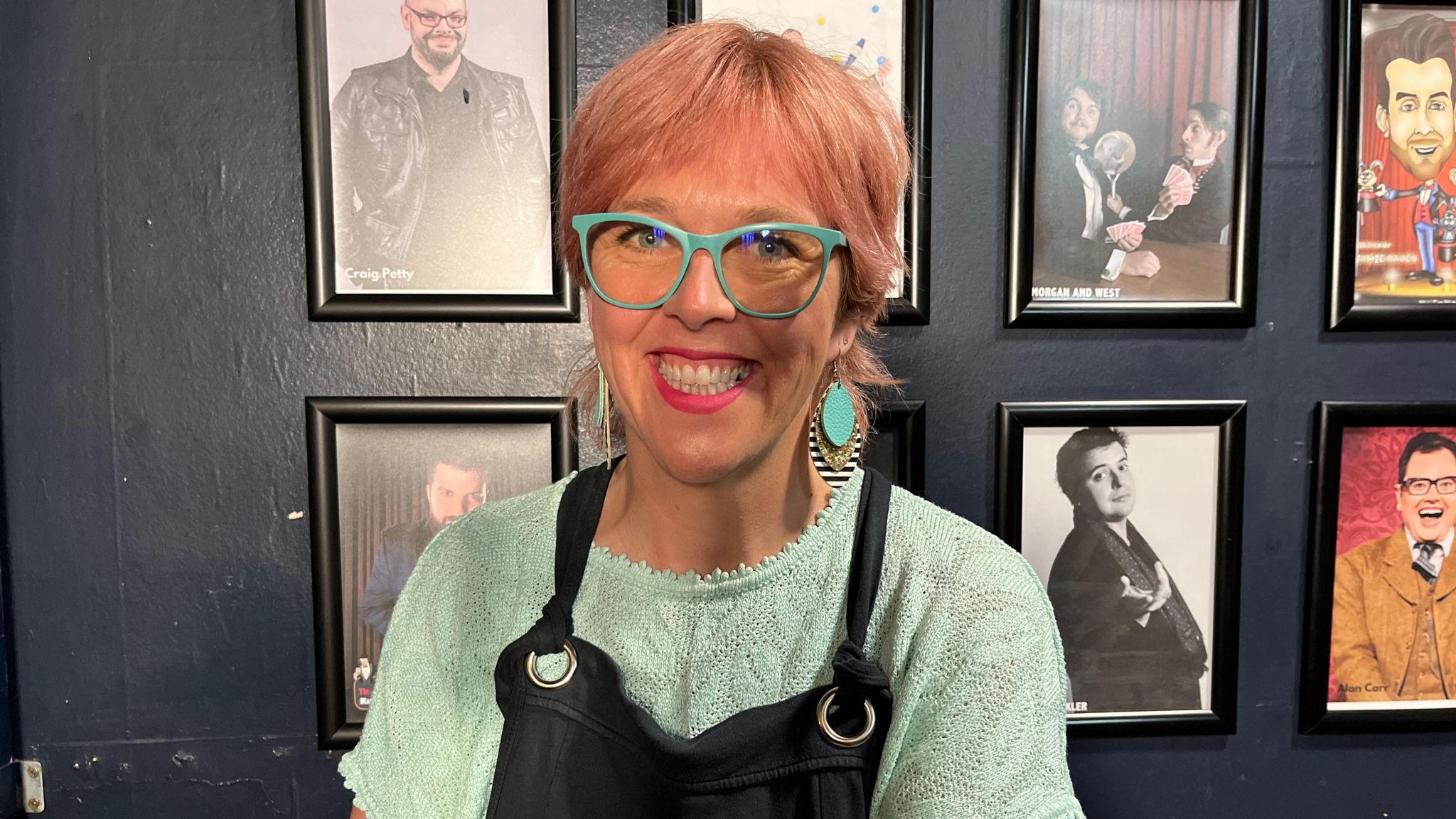 Louise Leigh smiling, wearing matching pale green earrings, top and glasses