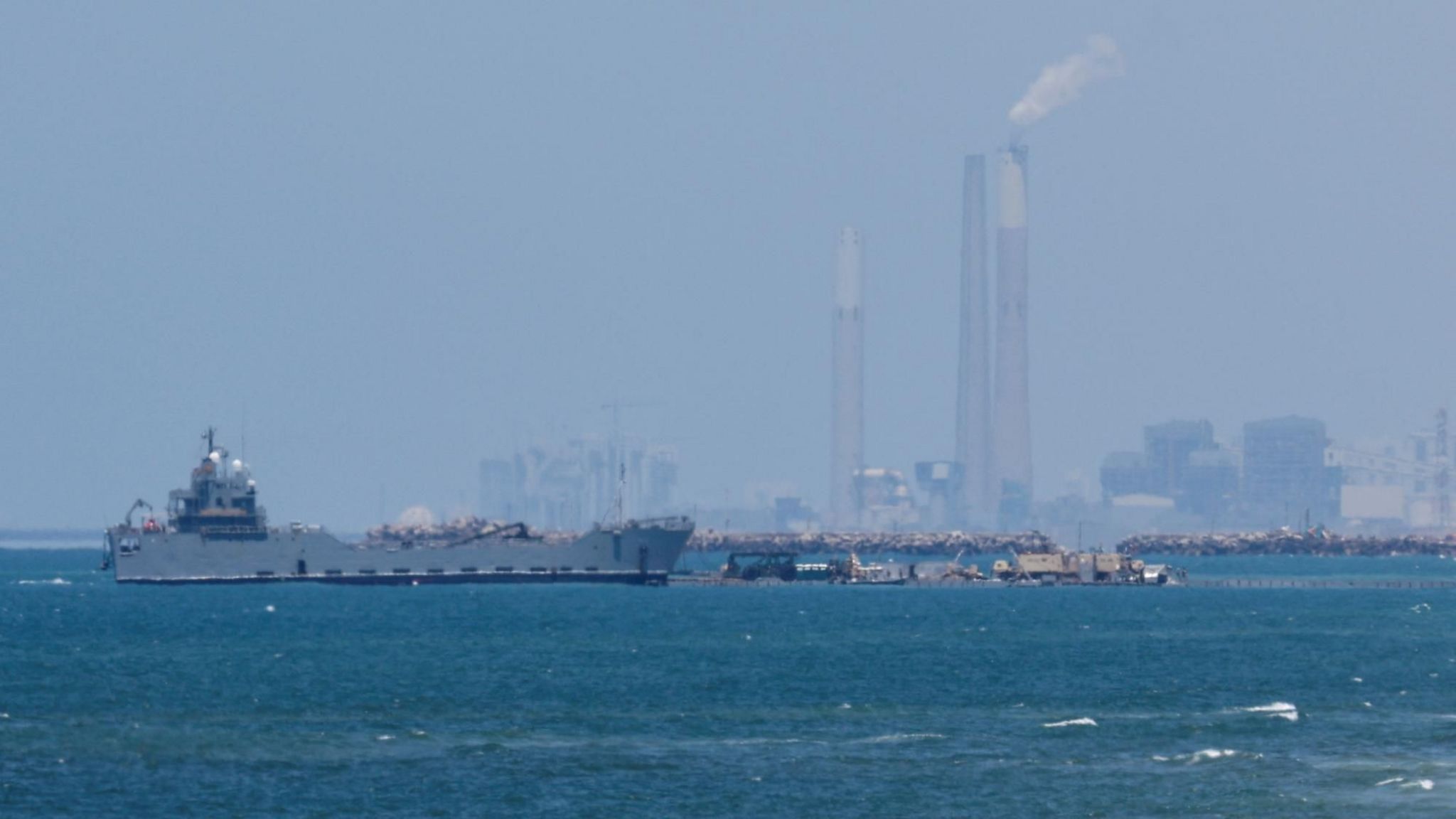 A ship is pictured off the coast of Gaza near a temporary floating pier anchored to a beach by the US military (16 May 2024)