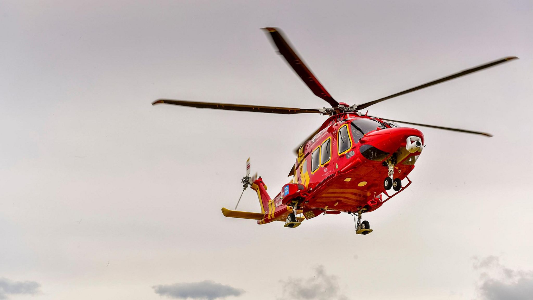 The Cornwall Air Ambulance in flight in a pastel pink coloured sky