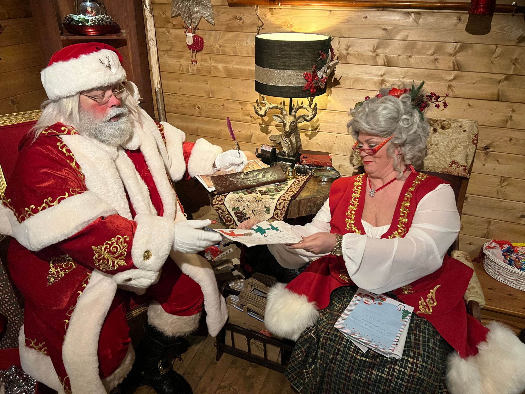 Santa Claus and Mrs Claus inside the cabin inspecting letters