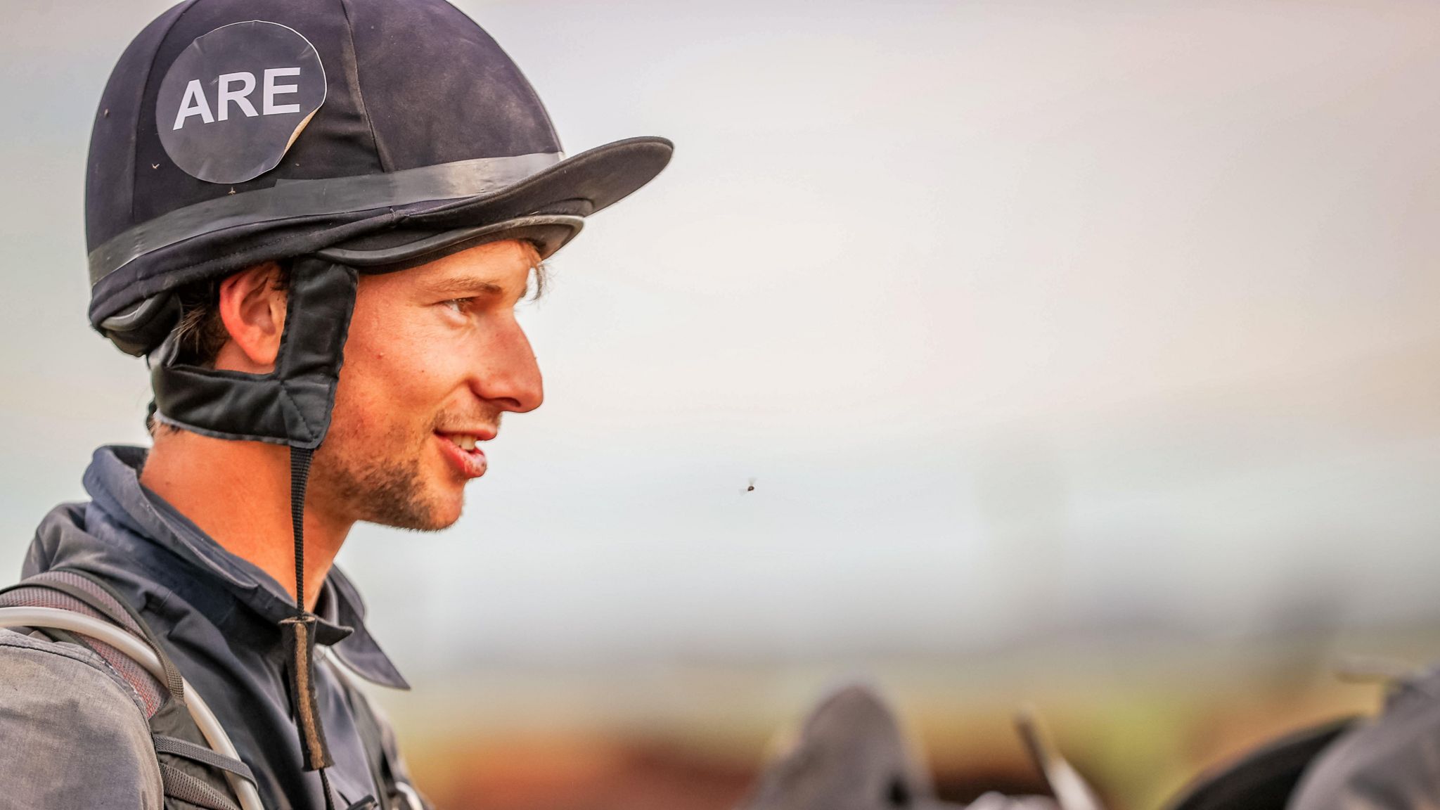 Gus Read from the shoulders up. He is wearing a black jacket and a black riding helmet, with his initials - ARE - on it.