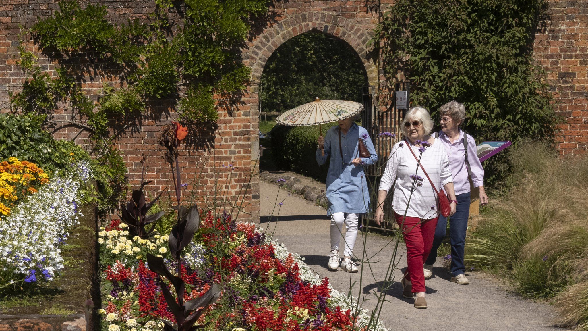 An elderly group walk along the herbaceous border in the gardens at Beckenham Place Park