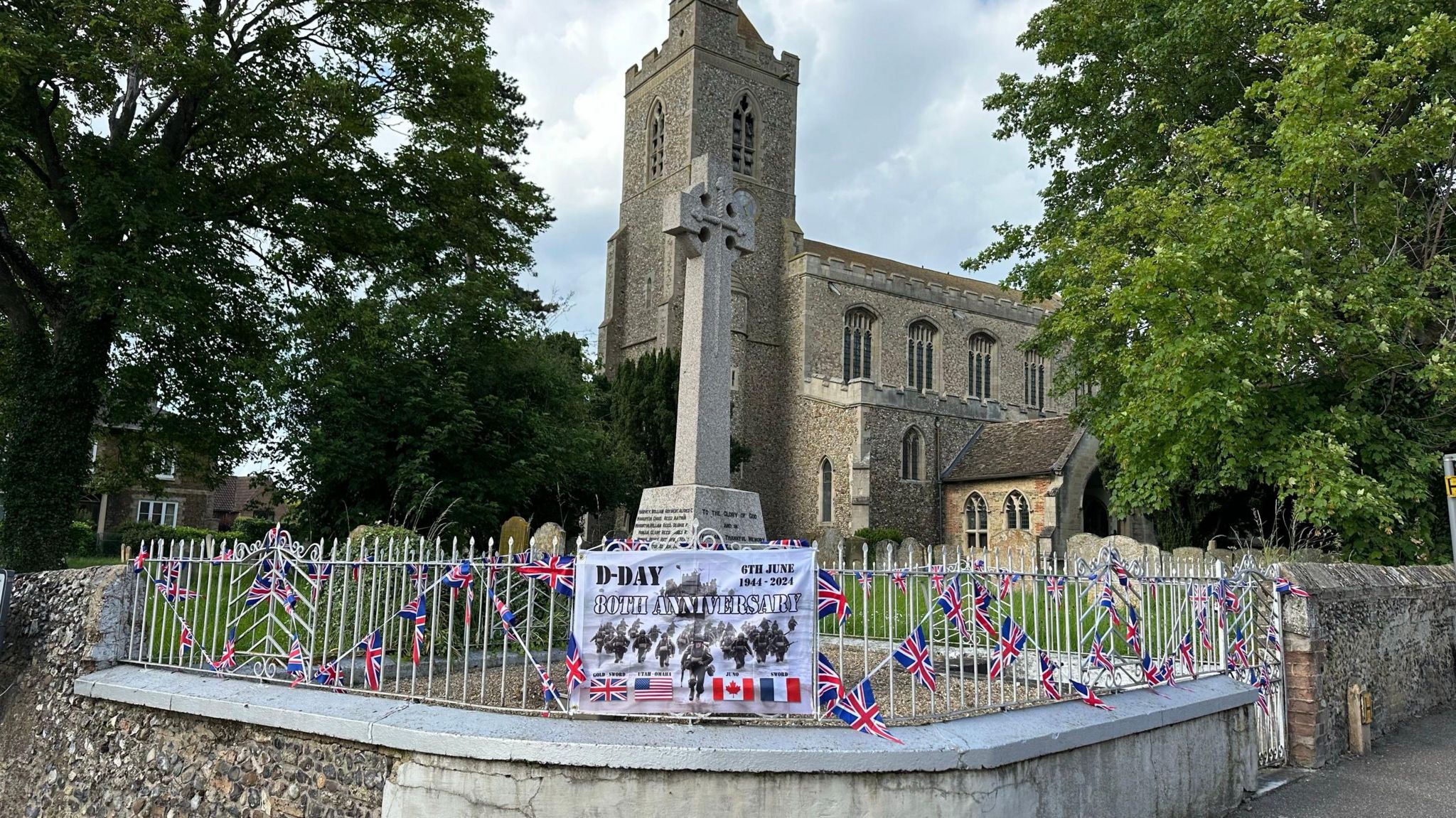 A war memorial and church decorated with flags 