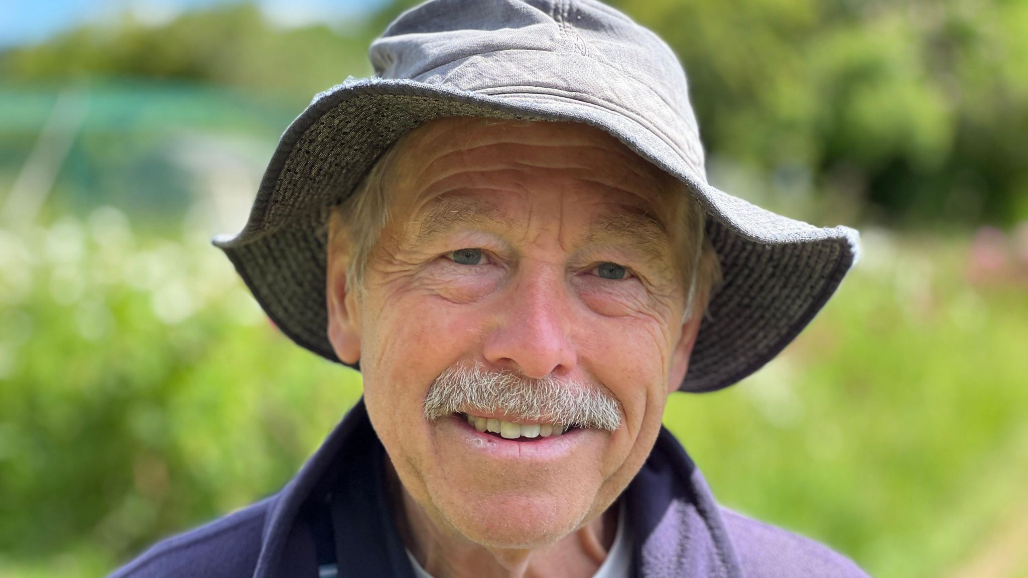 Close up portrait of Chris Pearce wearing a hat in the allotments