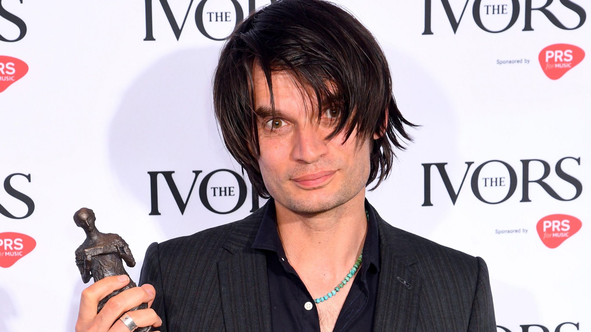 Jonny Greenwood holding an Ivor Novello award