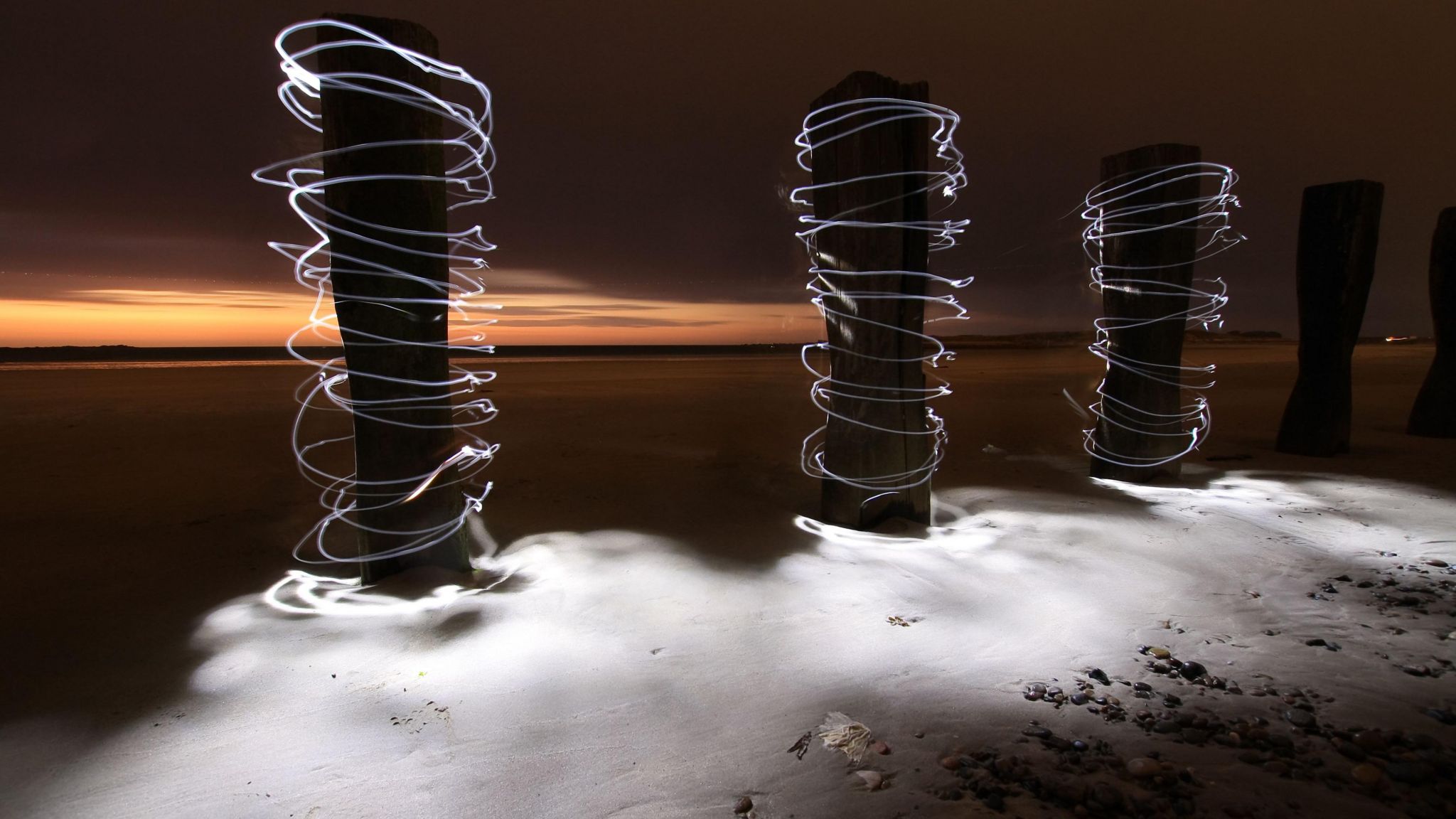 Light around some wooden poles on a beach
