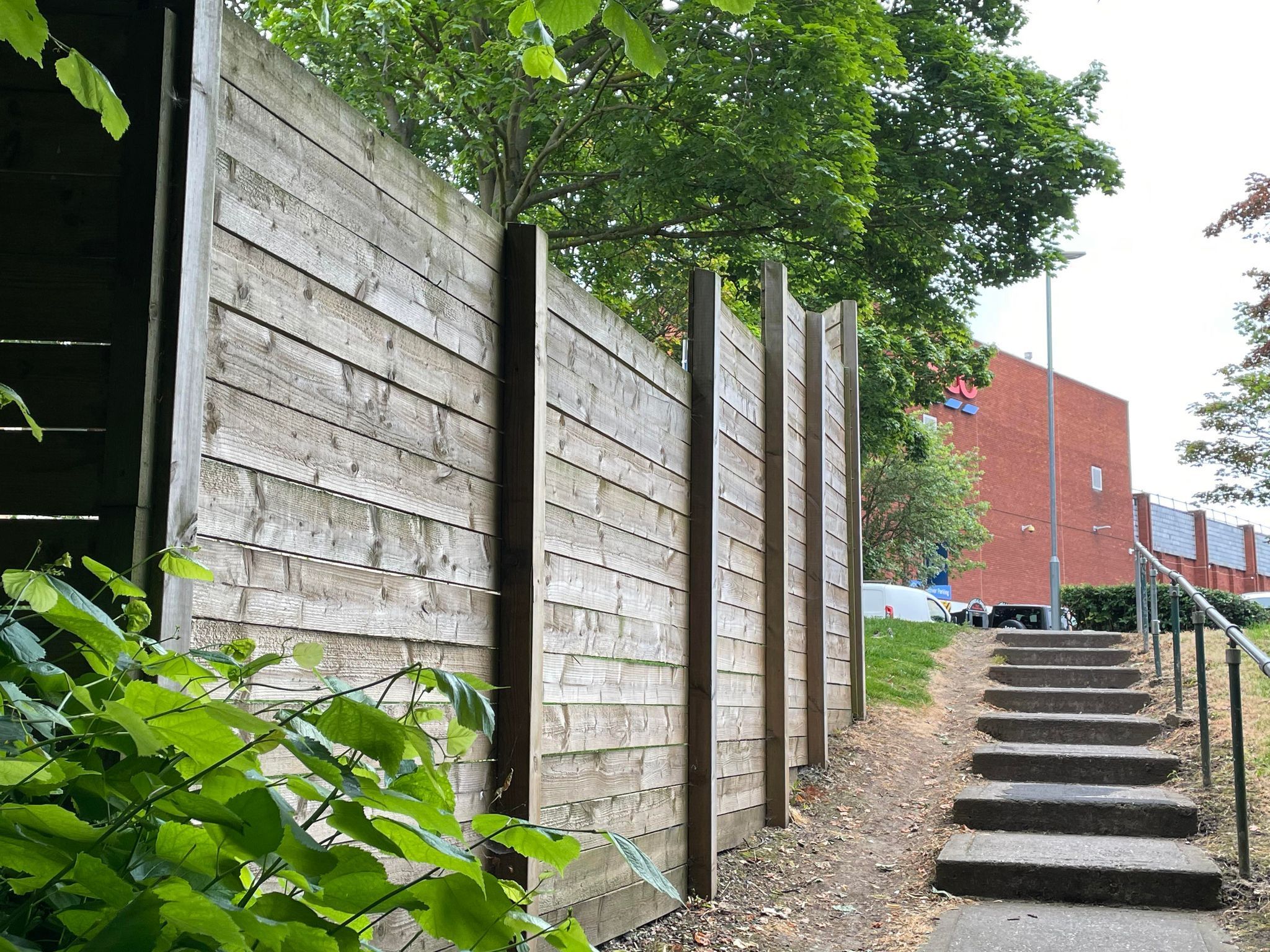 A path leading along fencing towards a Tesco store