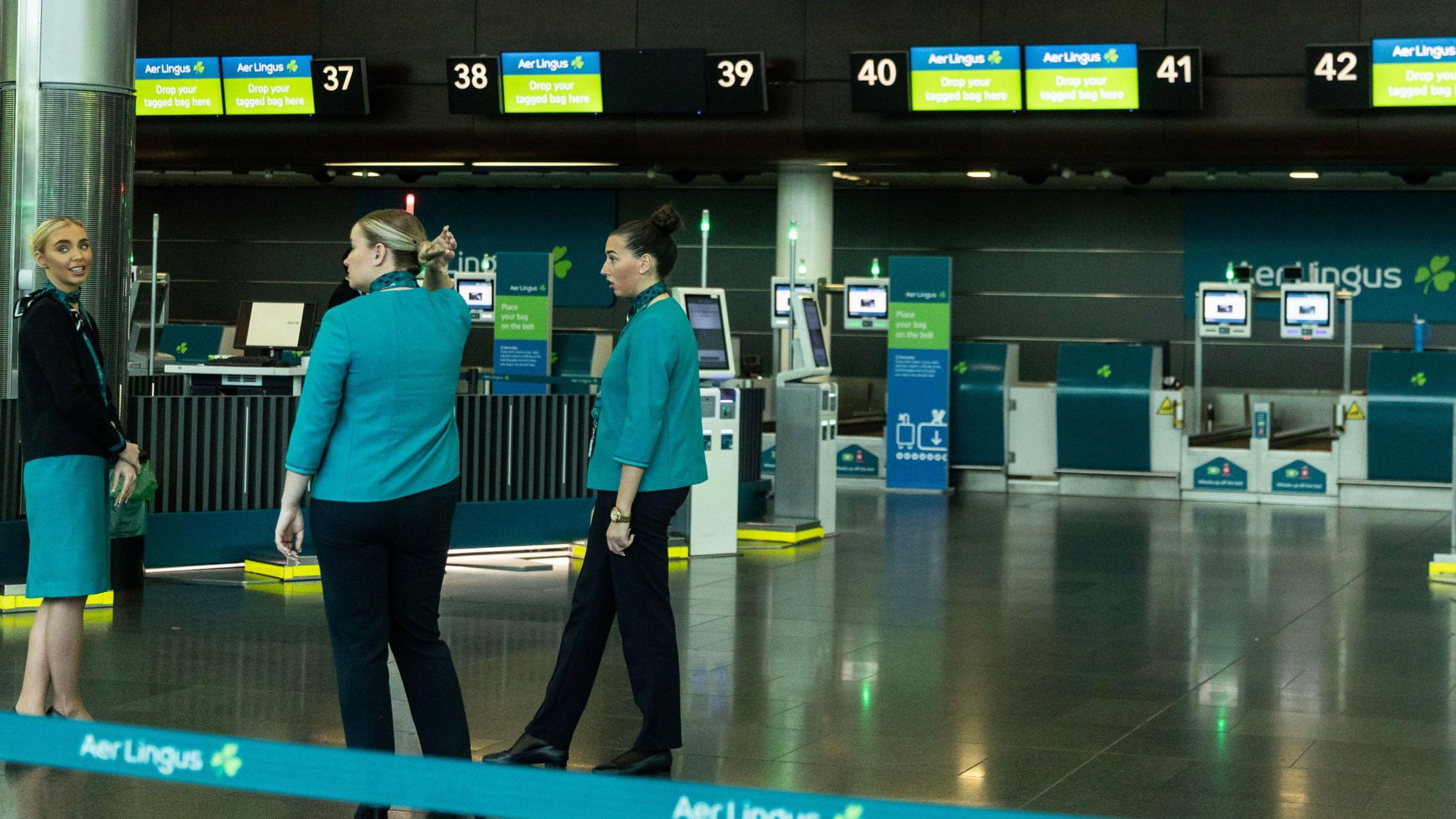 Three Aer Lingus staff at the check in desks at Dublin airport. There are no passengers to be seen anywhere due to pilots's strike