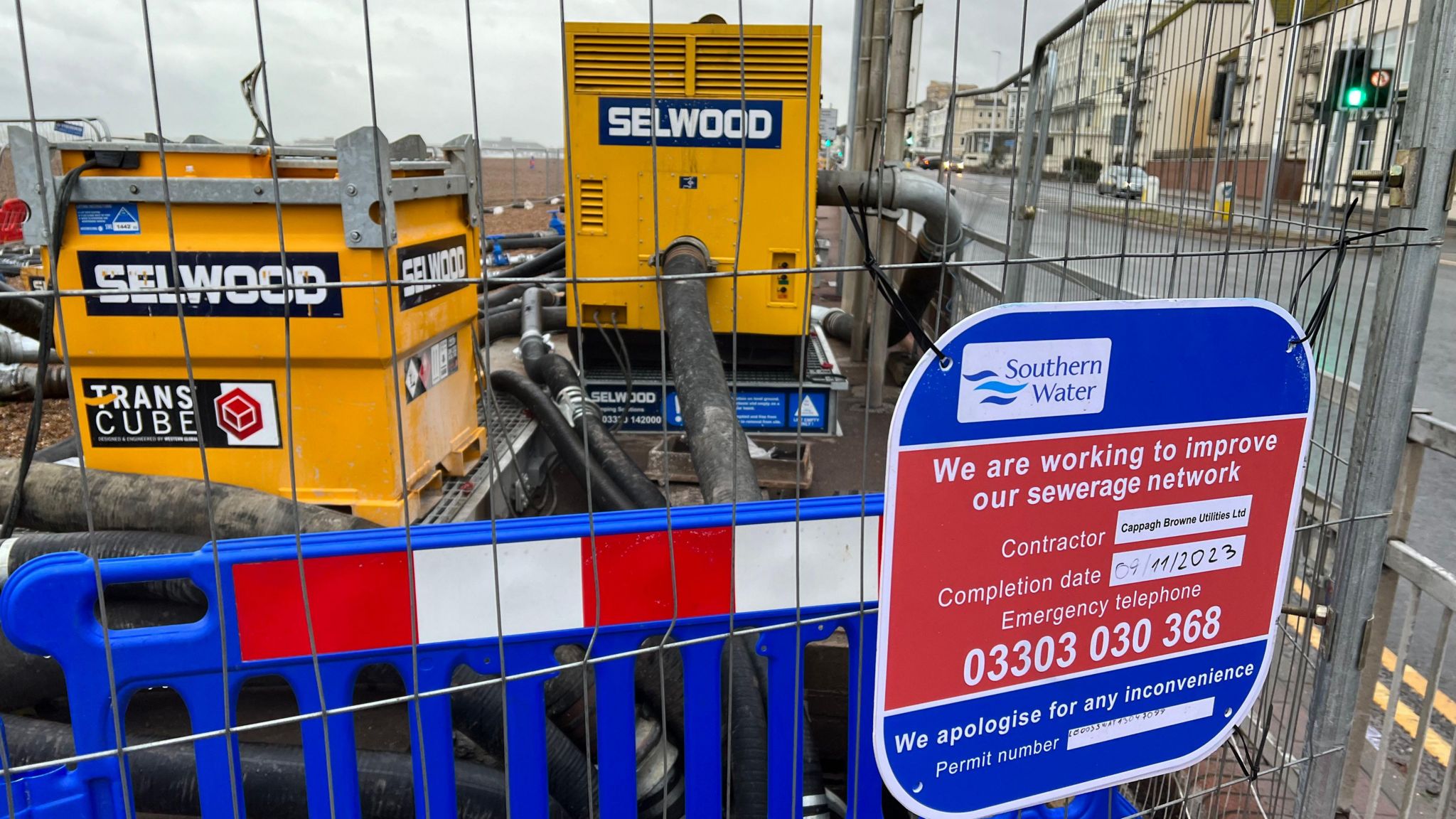 A Southern Water sign in front of a large yellow pump behind railings
