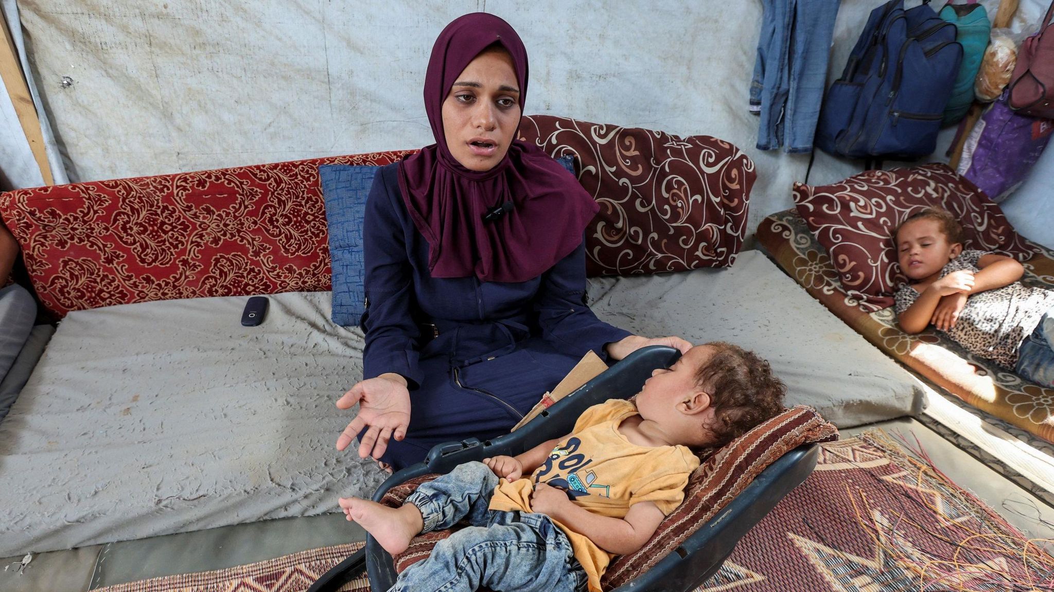 The mother of Palestinian boy Abdul Rahman Abu Al-Jidyan, who is the first person to contract polio in Gaza in 25 years, gestures as she looks after him in their tent, in Deir Al-Balah, in the central Gaza Strip August 28, 2024. 
