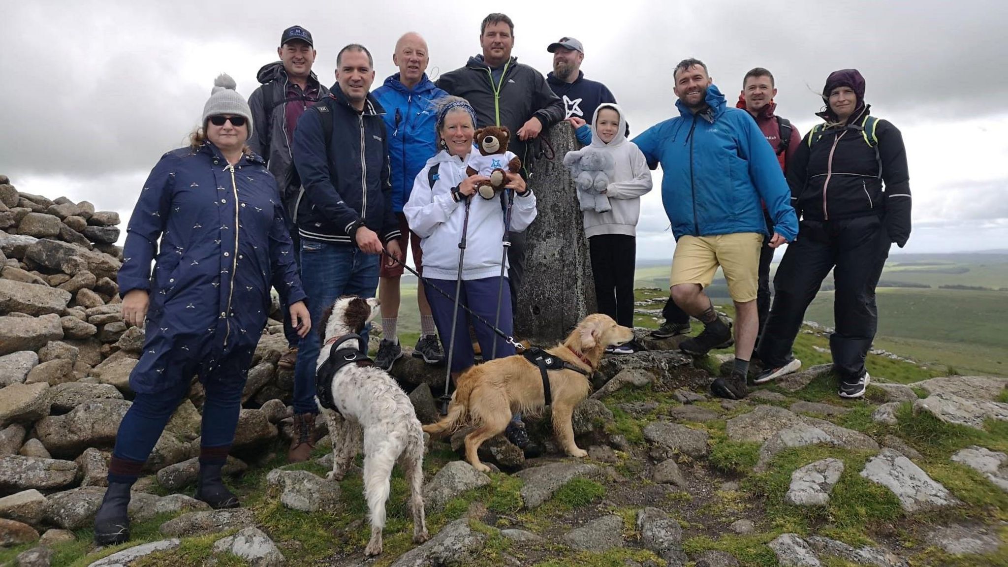 A large group of people and two dogs on a hilltop