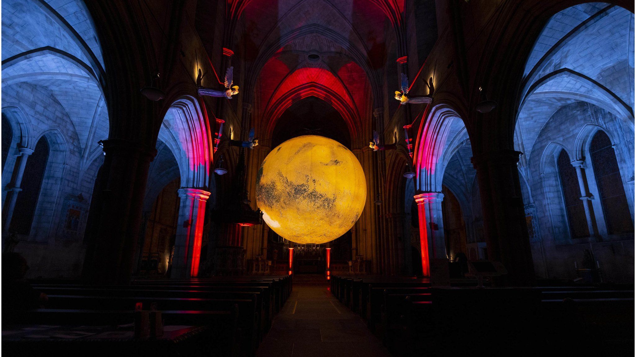 A big art installation in a dark glowing room that displays planet Mars