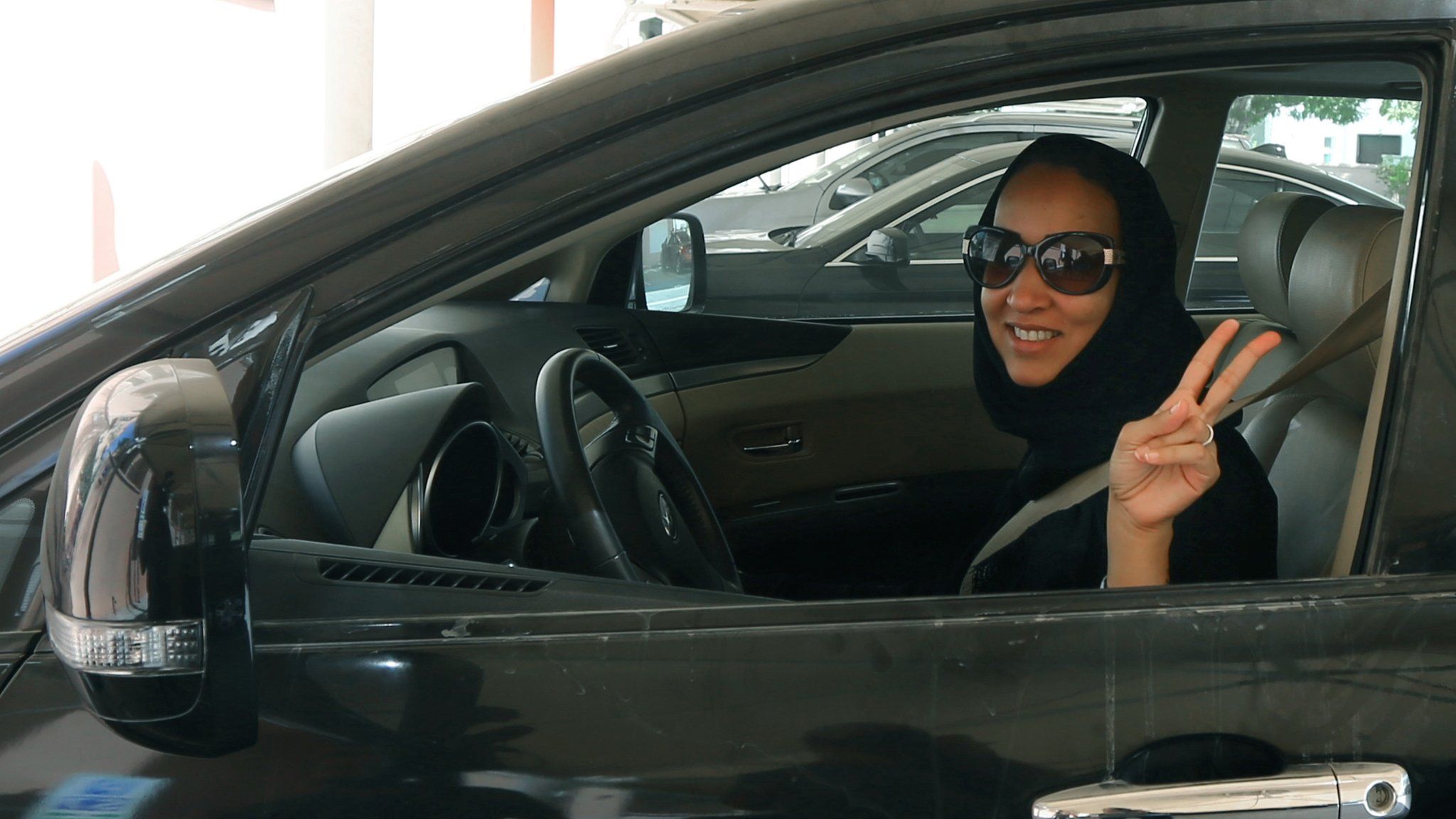 File photo: Saudi activist Manal Al Sharif poses in a car in Dubai, in solidarity with a planned protest in Saudi Arabia, 22 October 2013