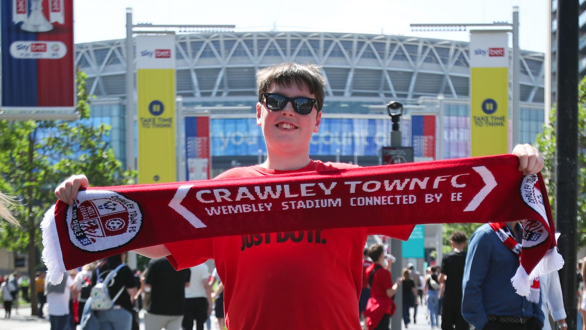 A boy with brown hair holding a Crawley Town scarf