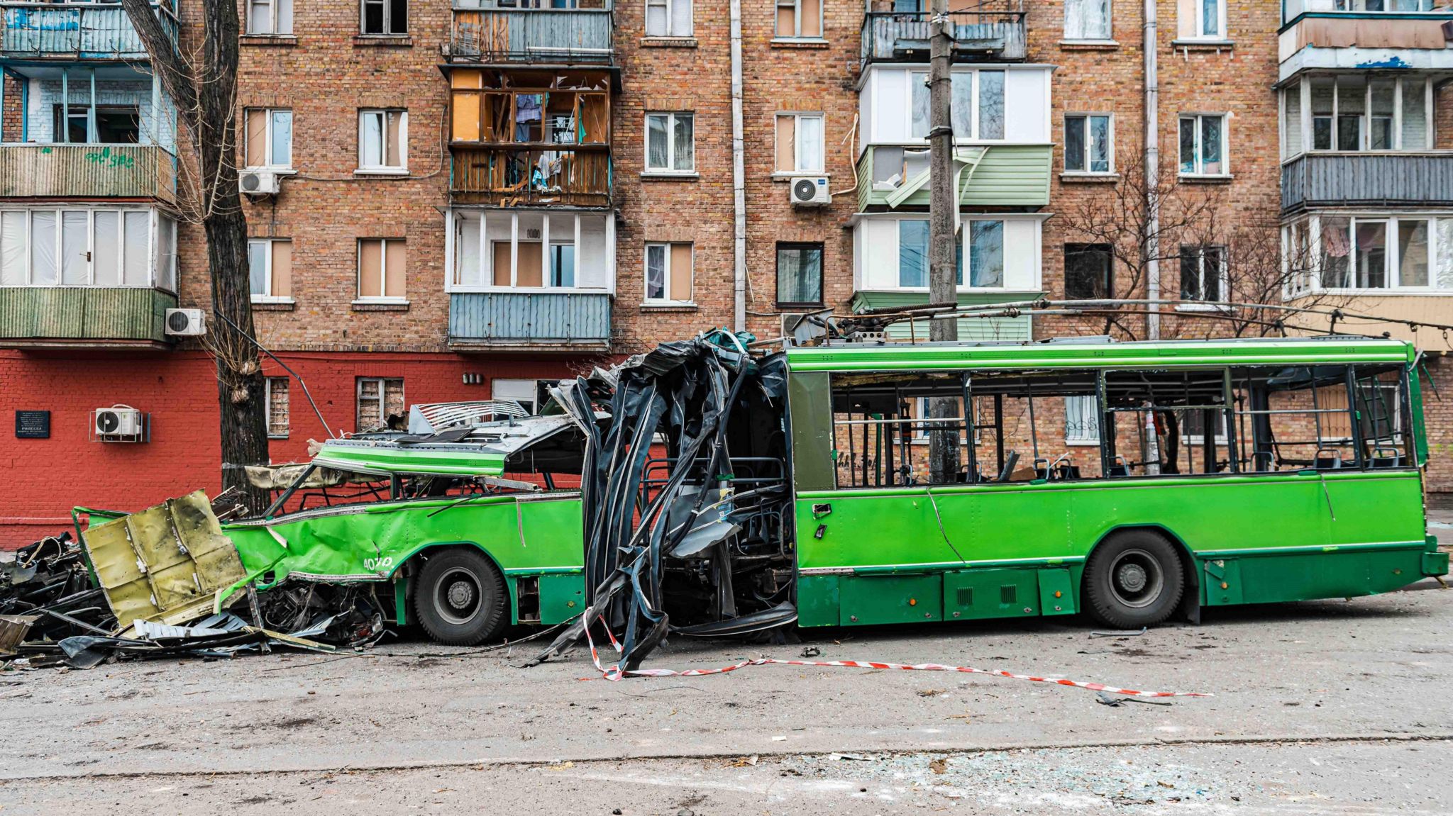 A green bus that has been wrecked by combat 