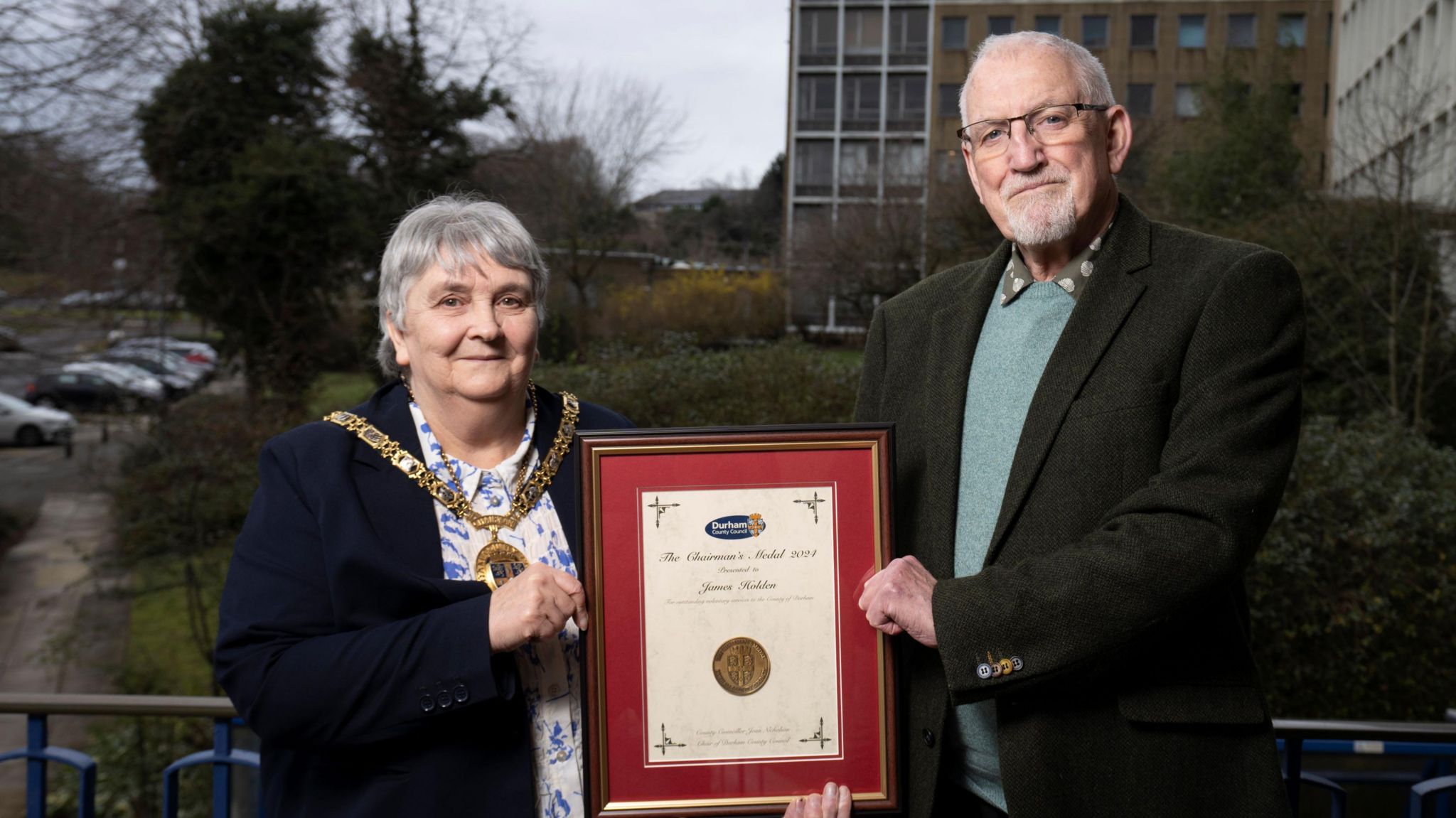 The Chairman of Durham County Council and a volunteer holding the Chairman's Medal in a frame