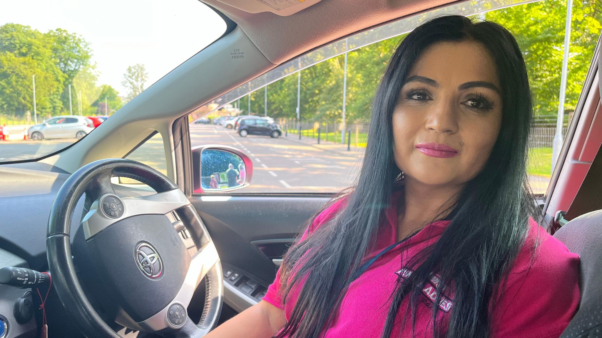 Amberine Nawaz sitting in the pink taxi, wearing a pink T-shirt