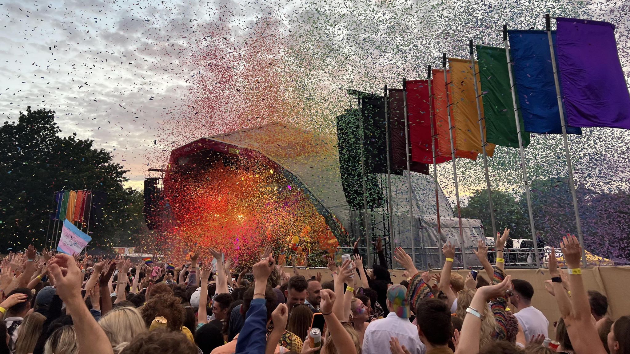 A crowd of people in front of a stage at Bristol Pride festival, with multi-coloured ticker tape filling the air 