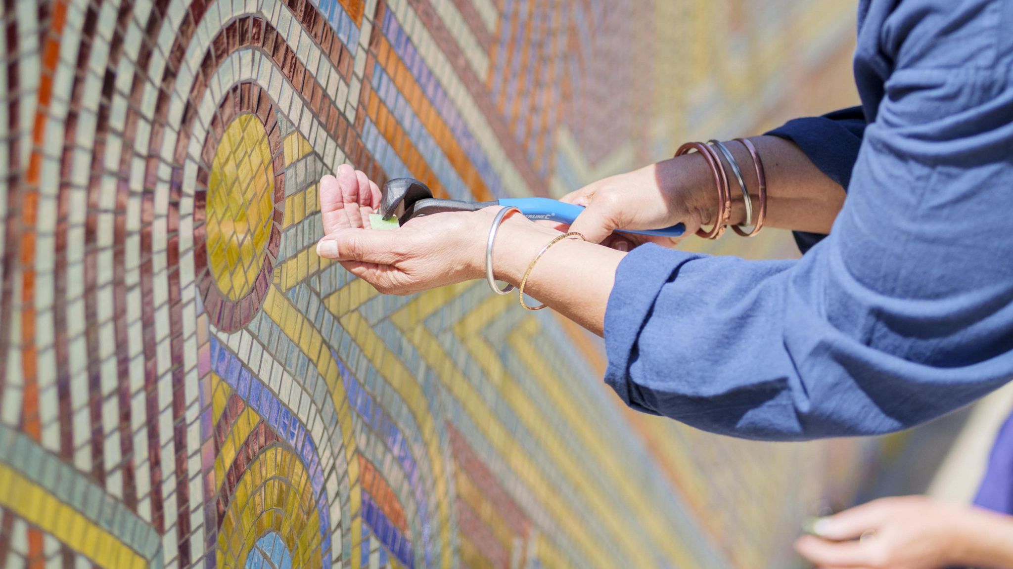 A person cuts a mosaic tile