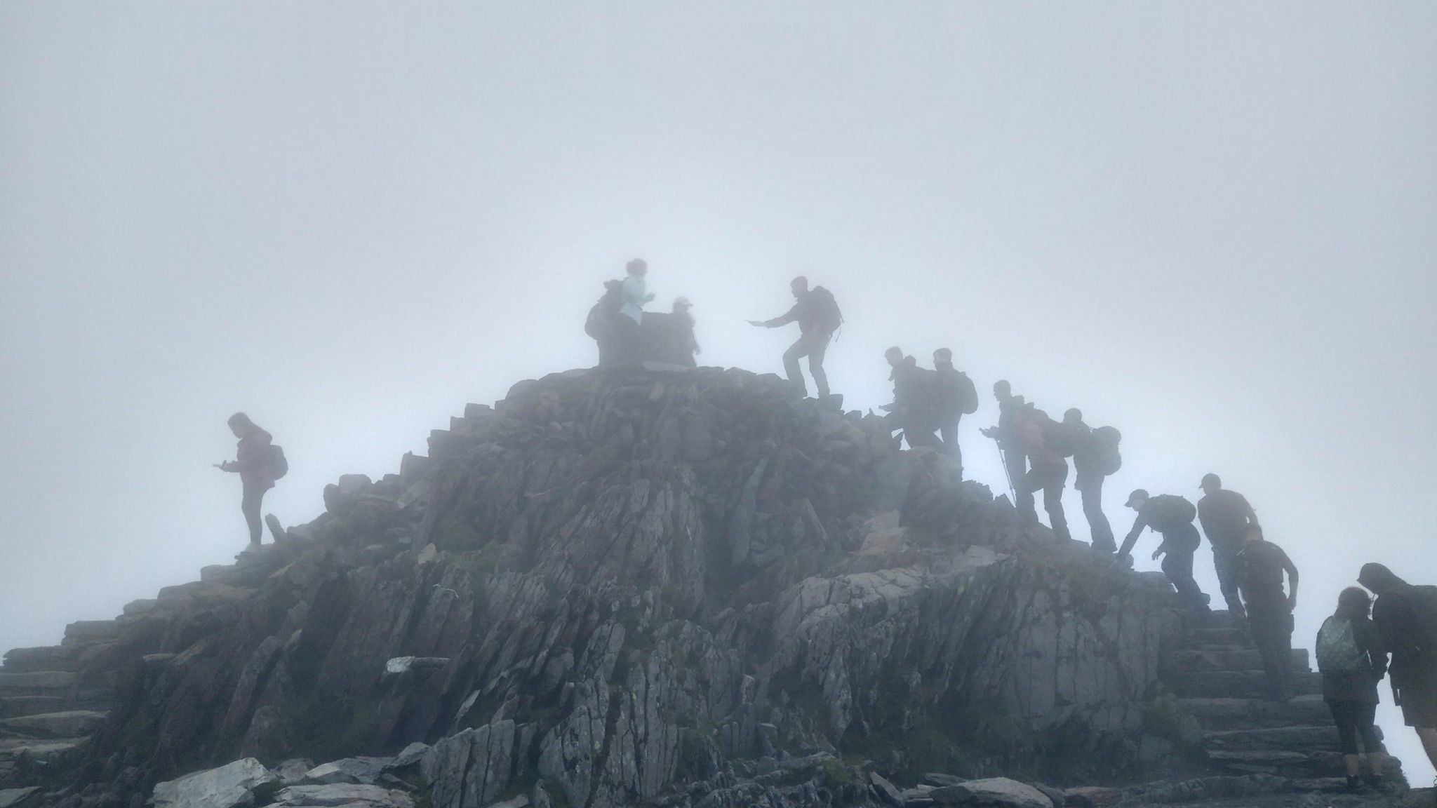 Figures climbing to the summit of Yr Wyddfa (Snowdon) in Wales