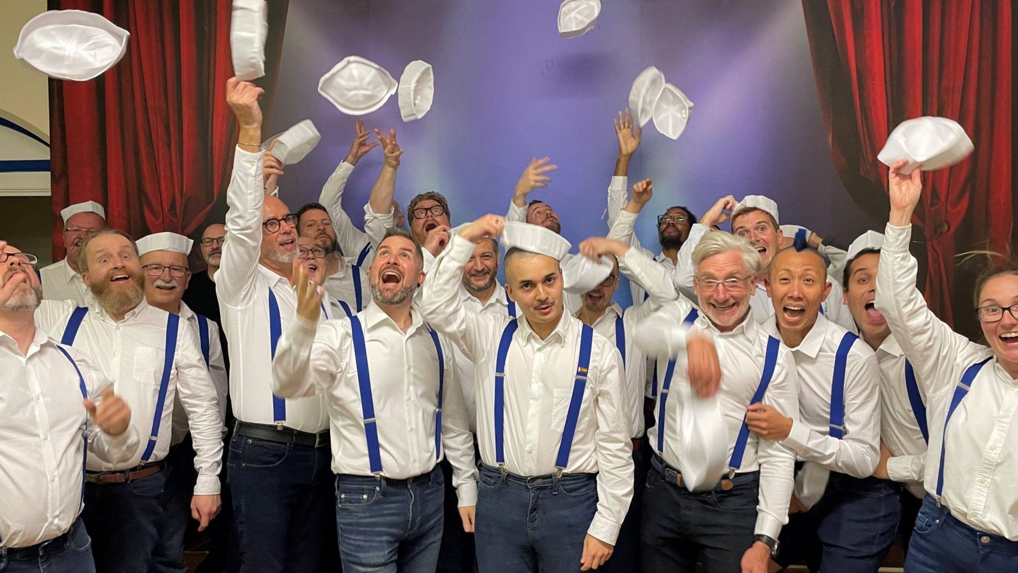 LGBTQ+ choir throw their hats in the air whilst dressed as sailors
