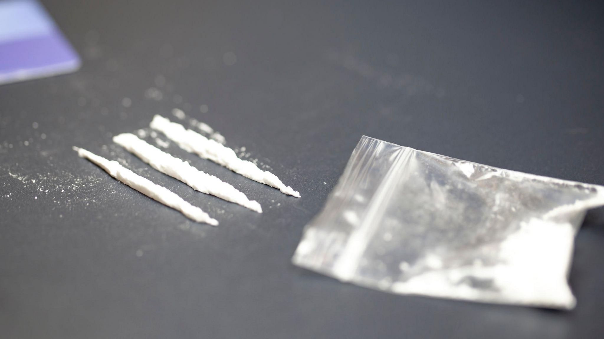 Bag containing cocaine and three lines on a tabletop