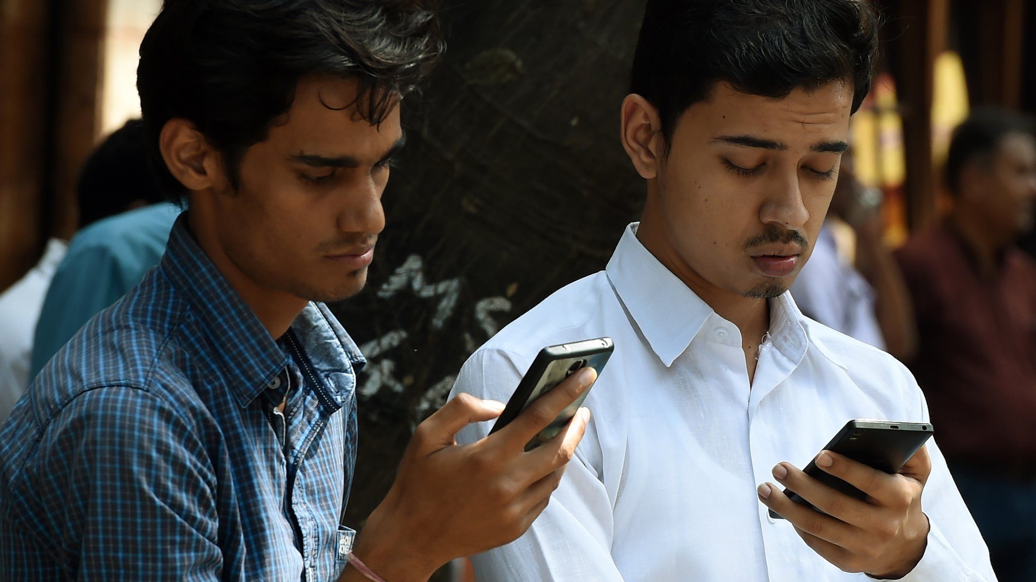 Indian pedestrians check their cellphones
