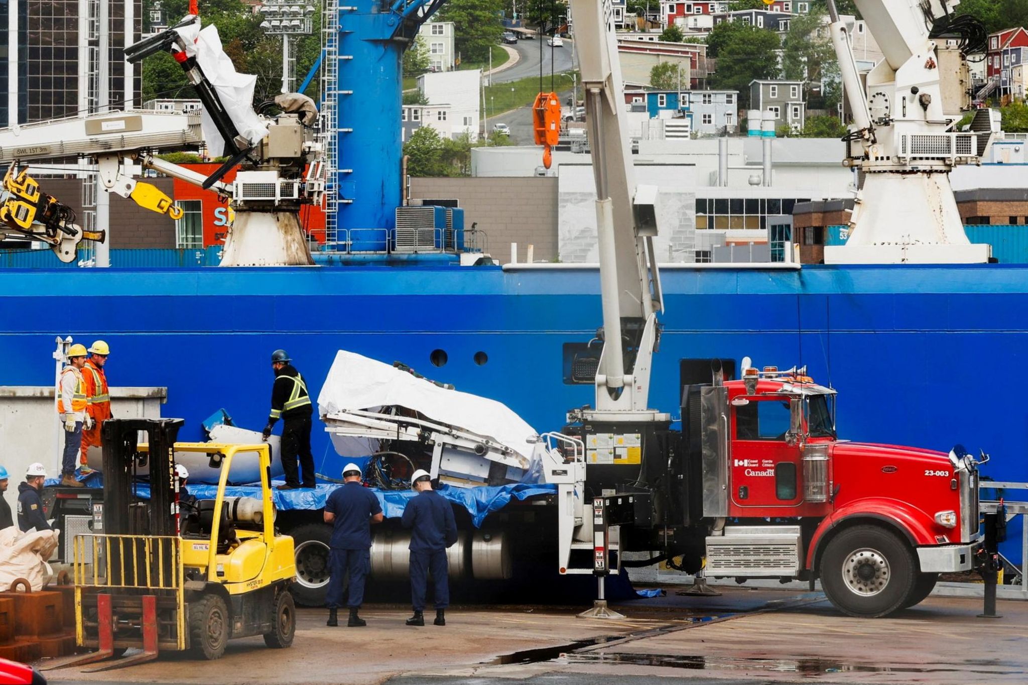 Parts of what appear to be the sub's fuselage are loaded onto trucks in St John's