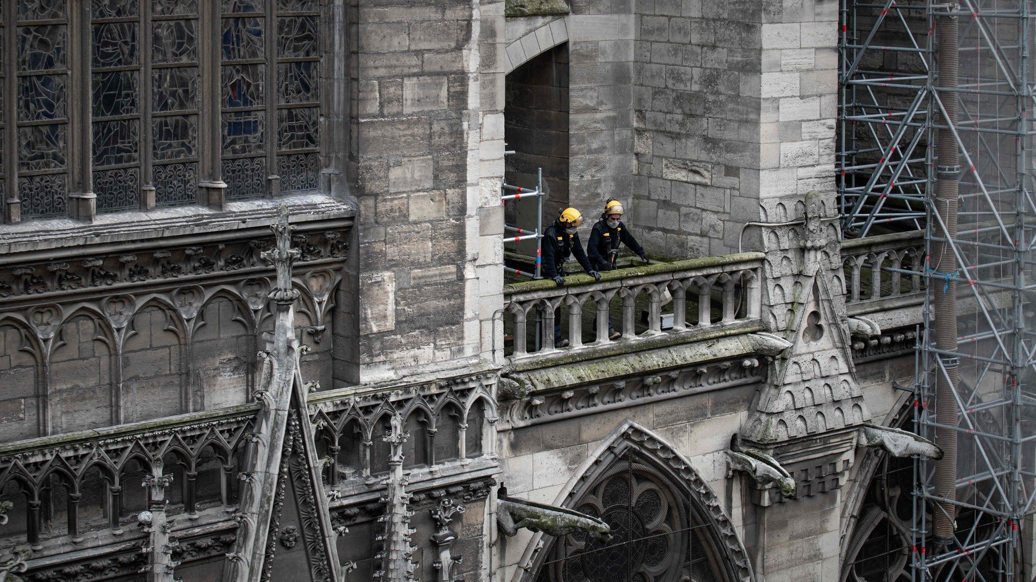 Workmen on a balcony in Notre Dame, which is covered in scaffolding