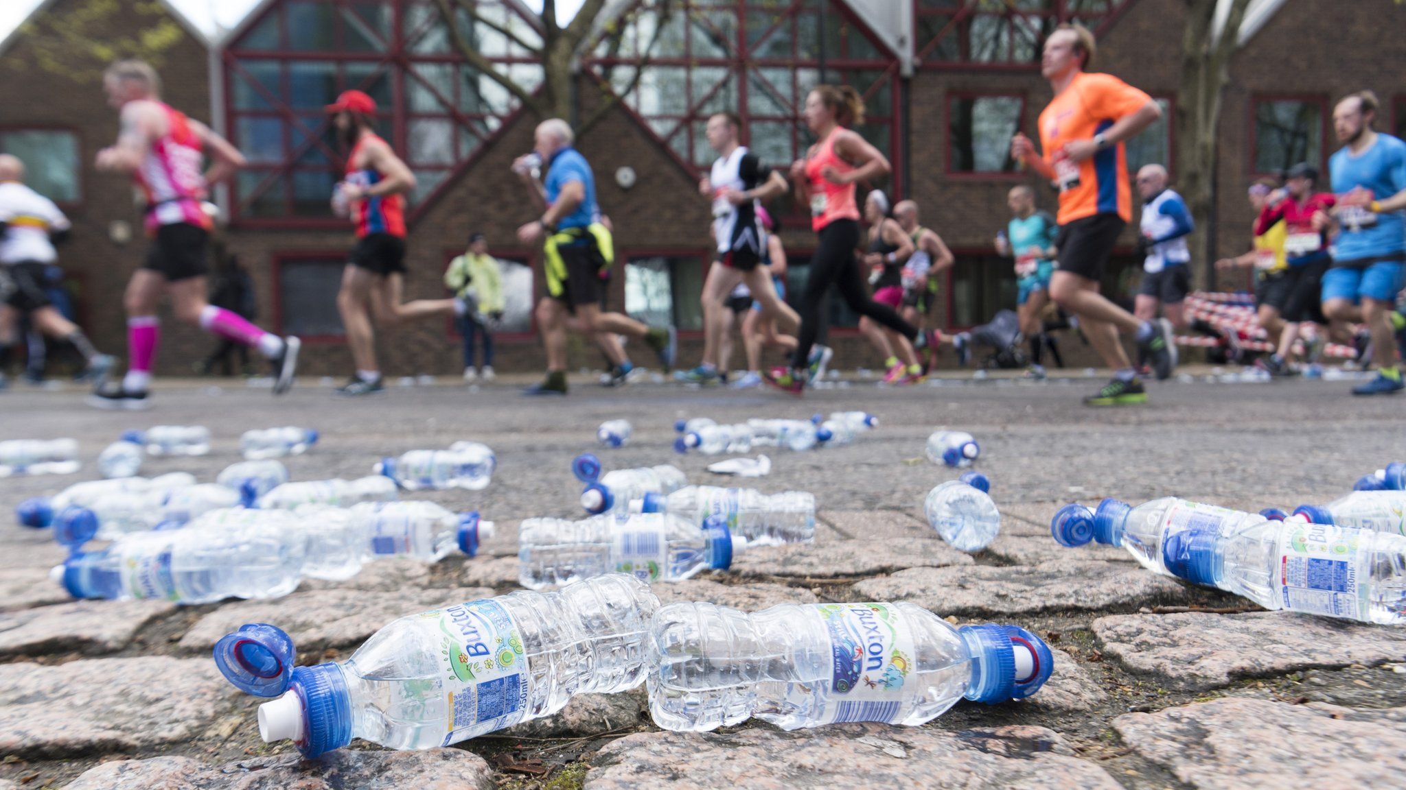 Runners run past water bottles as they take part in the 2016 London Marathon in London
