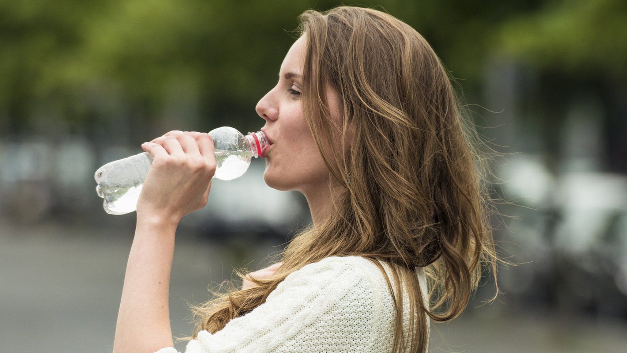 woman drinking out of plastic bottle
