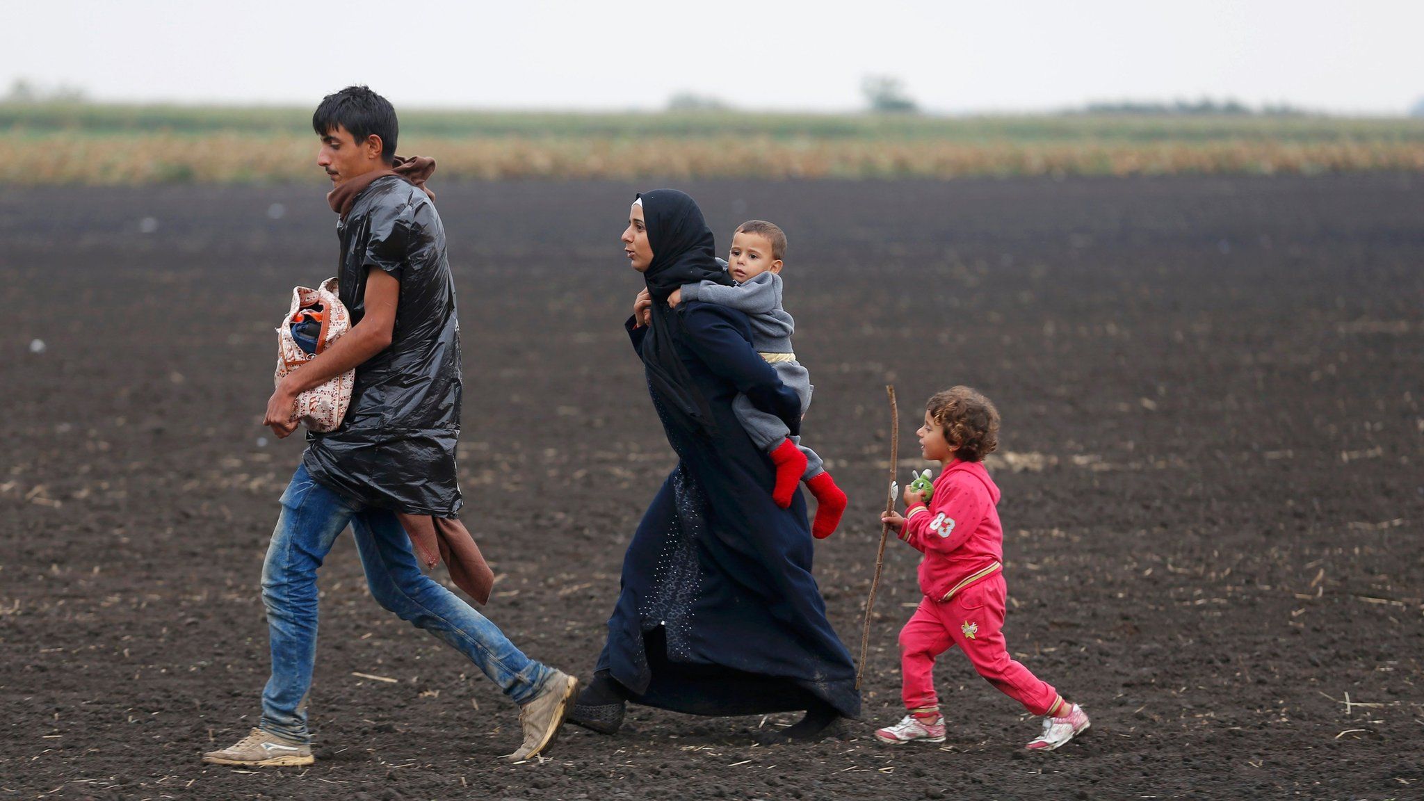 Migrants walk through a field in Roszke, Hungary, on 11 September 2015