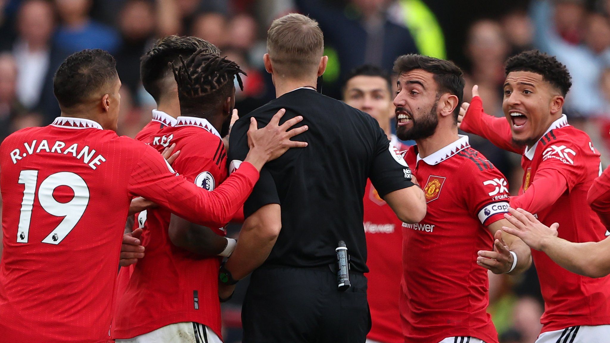 Manchester United players surround the referee
