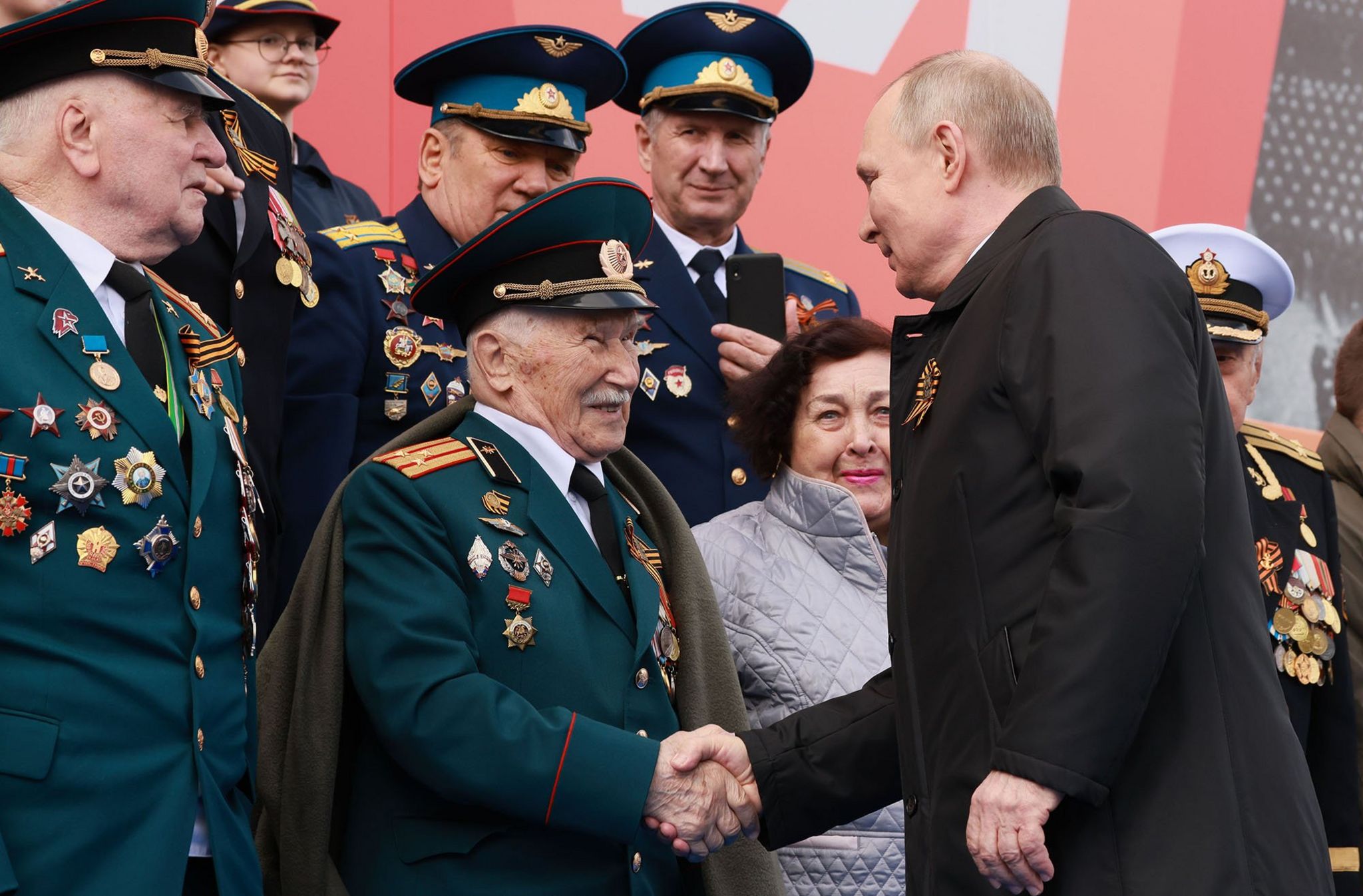 Russian President Vladimir Putin (R) shakes hands with a military veteran