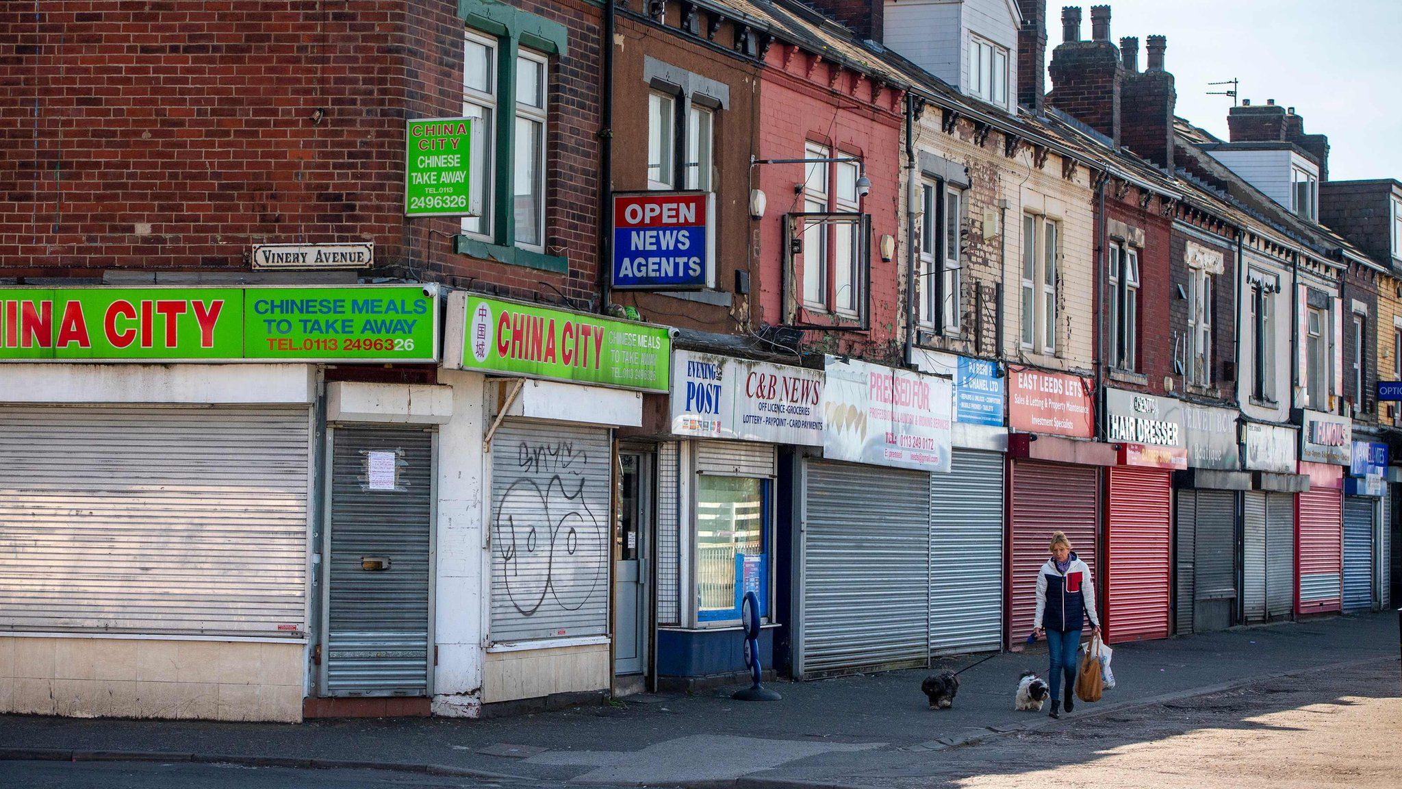 A woman walks her dogs past closed shops in Leeds city centre on 14 April
