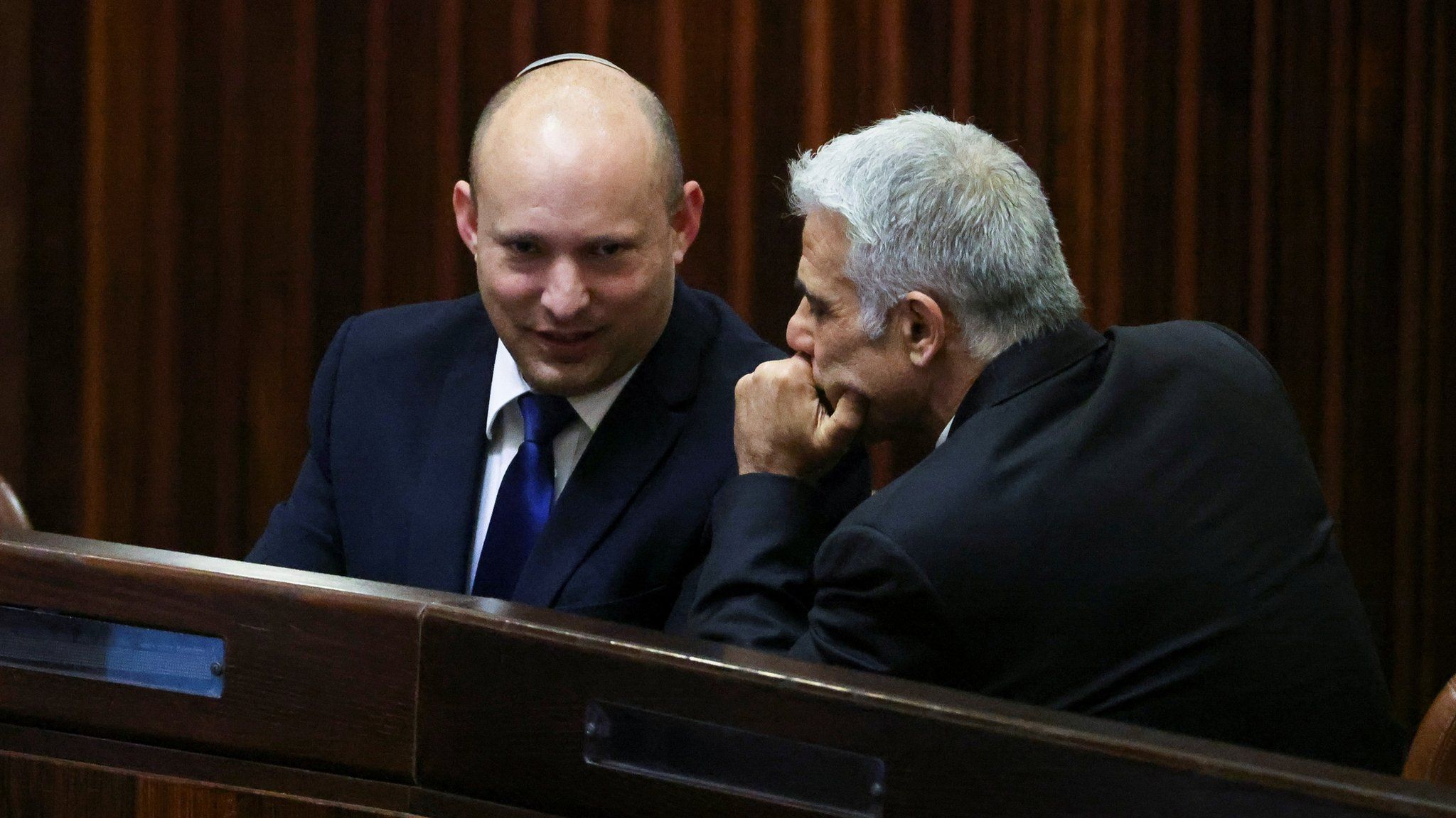 Israeli politicians Naftali Bennett (L) and Yair Lapid (R) talk during a parliamentary session in Jerusalem (2 June 2024)