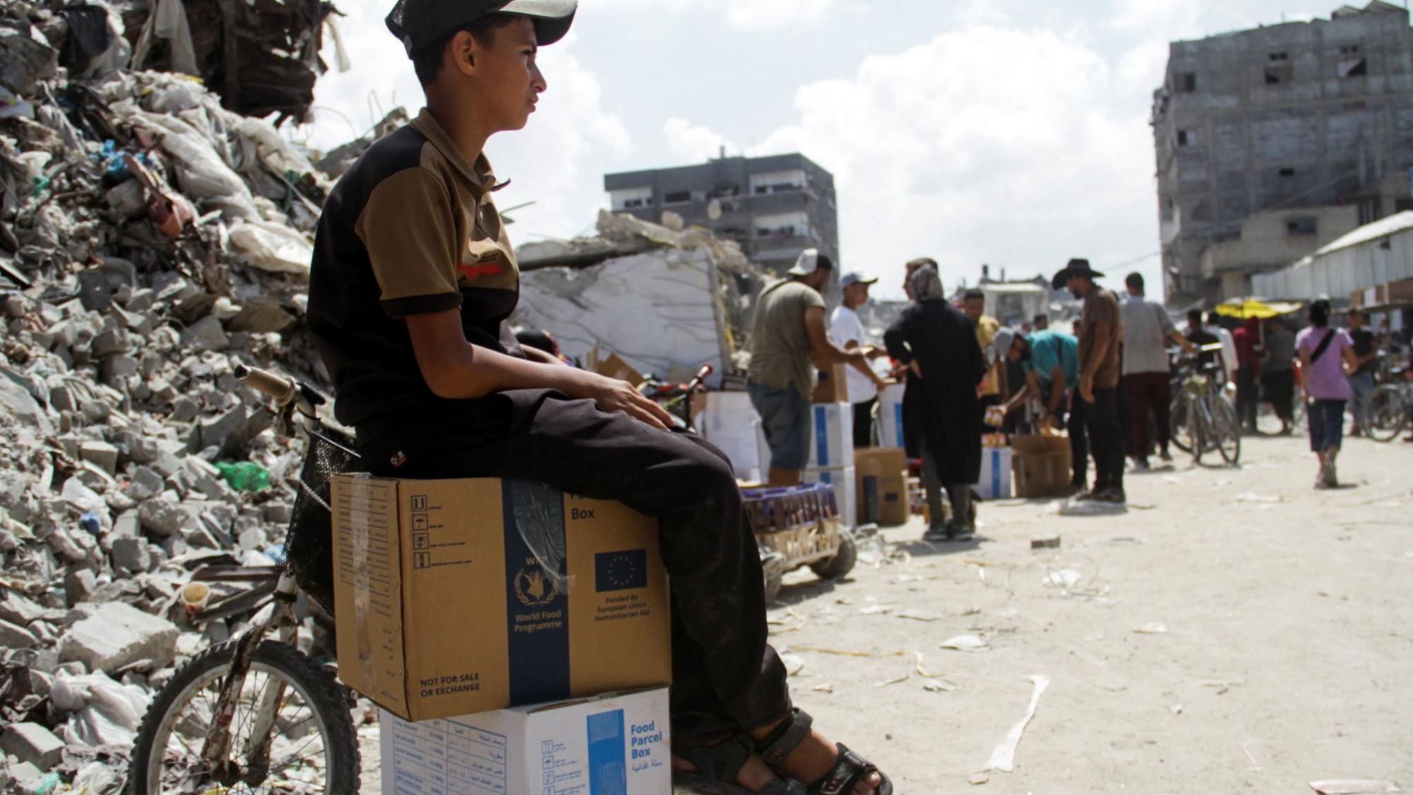 A Palestinian boy sits on boxes of food aid distributed by the UN's World Food Programme in Jabalia, in the northern Gaza Strip (24 August 2024)