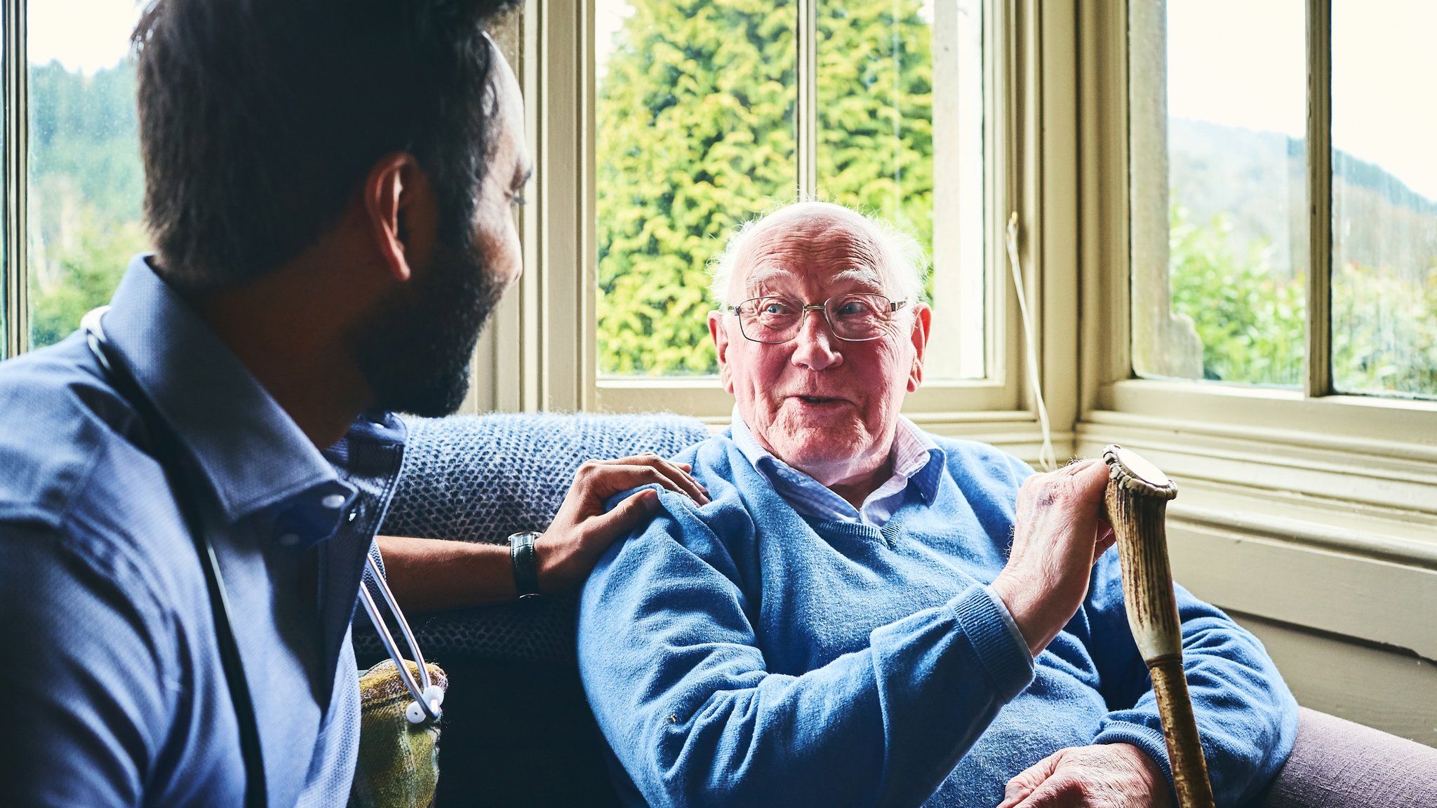 Male doctor talking with senior man in home visit